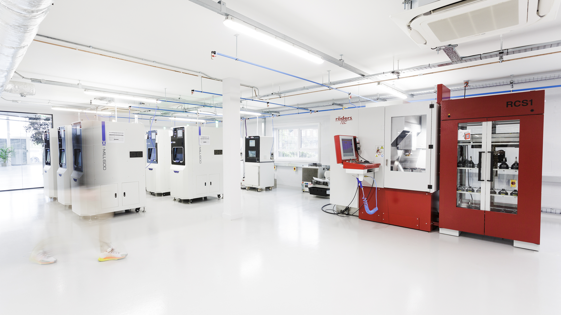 A bright, clean dental laboratory workspace showcasing multiple advanced CAD/CAM milling machines including an RCS1 unit and digital manufacturing equipment used for fabricating dental restorations.