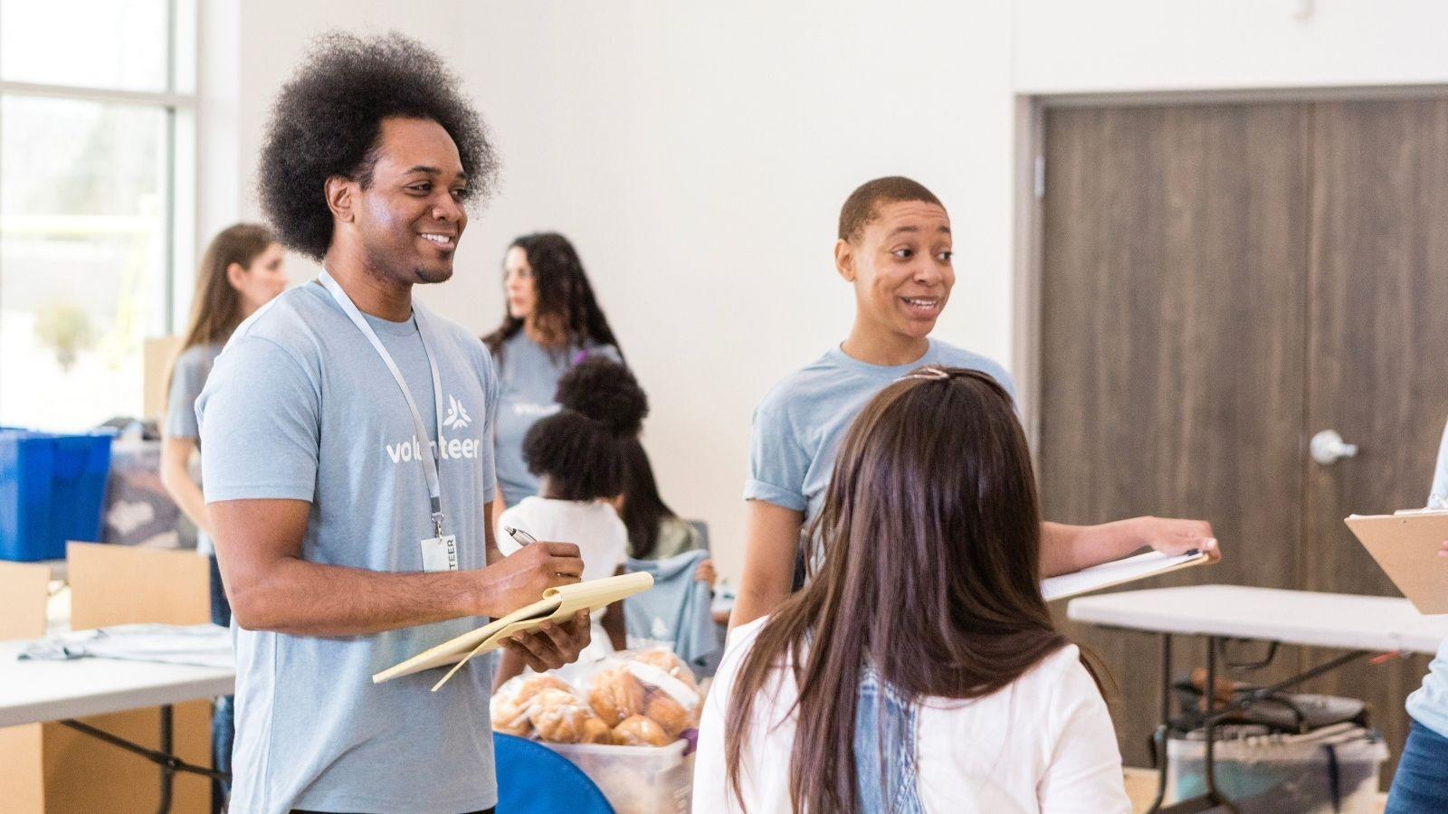 Warm, natural-light photo of a church community event in progress, volunteers at tables with donation jars,