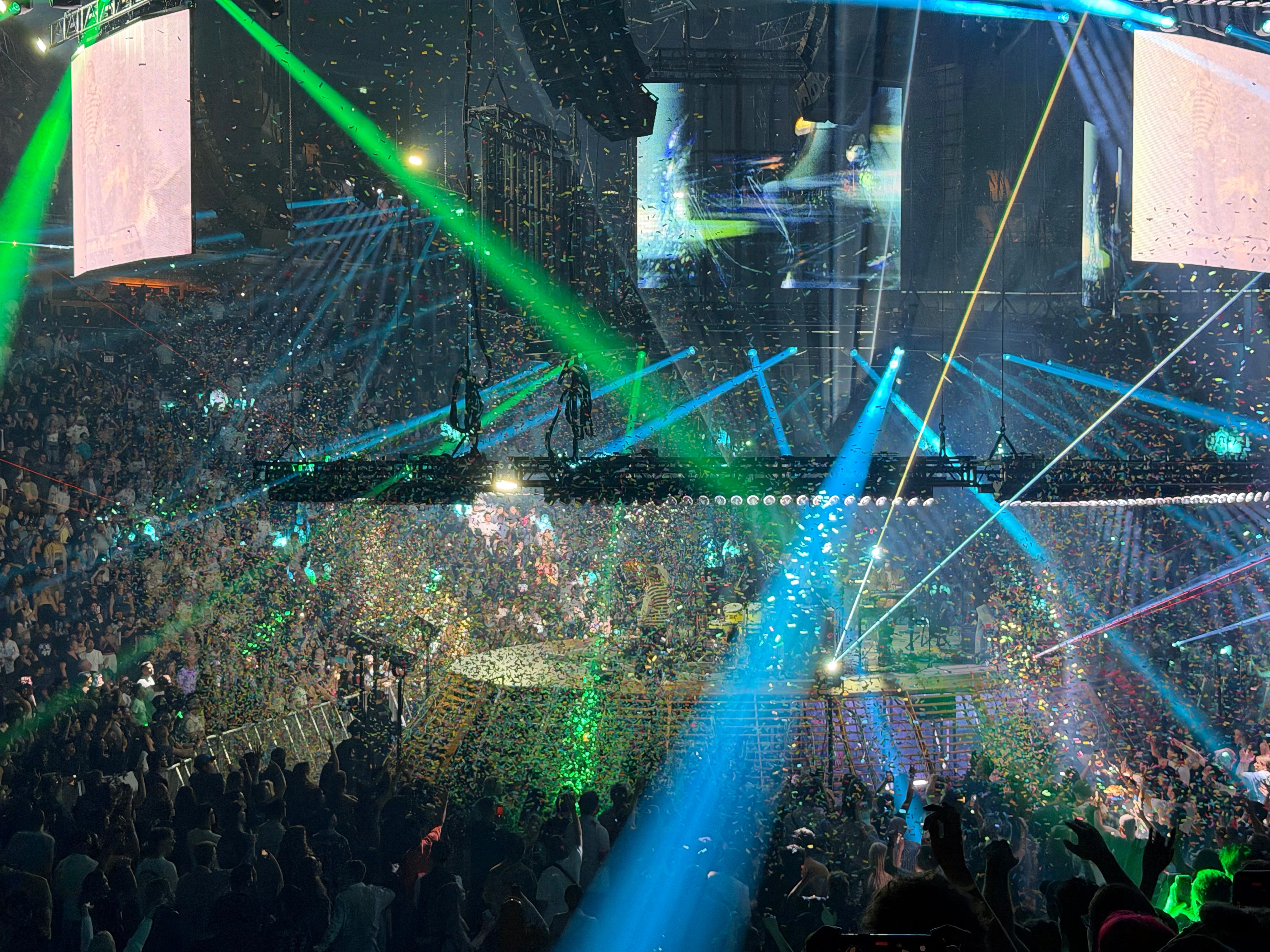 Rays of blue and green light flash around a large stadium.