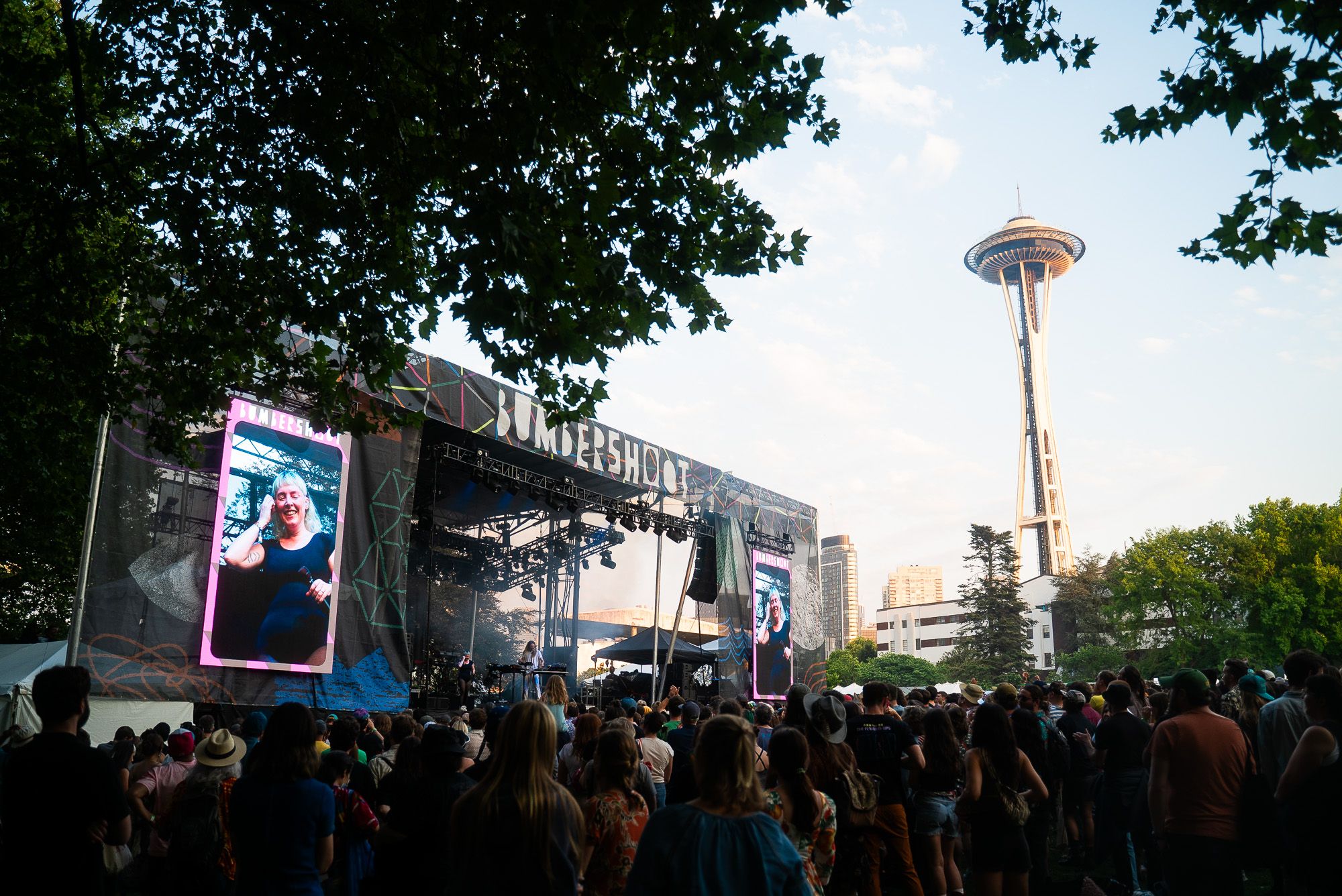 A crowd gathers at the main festival stage to watch Sylvan Esso perform with the Space Needle visible in the distance.