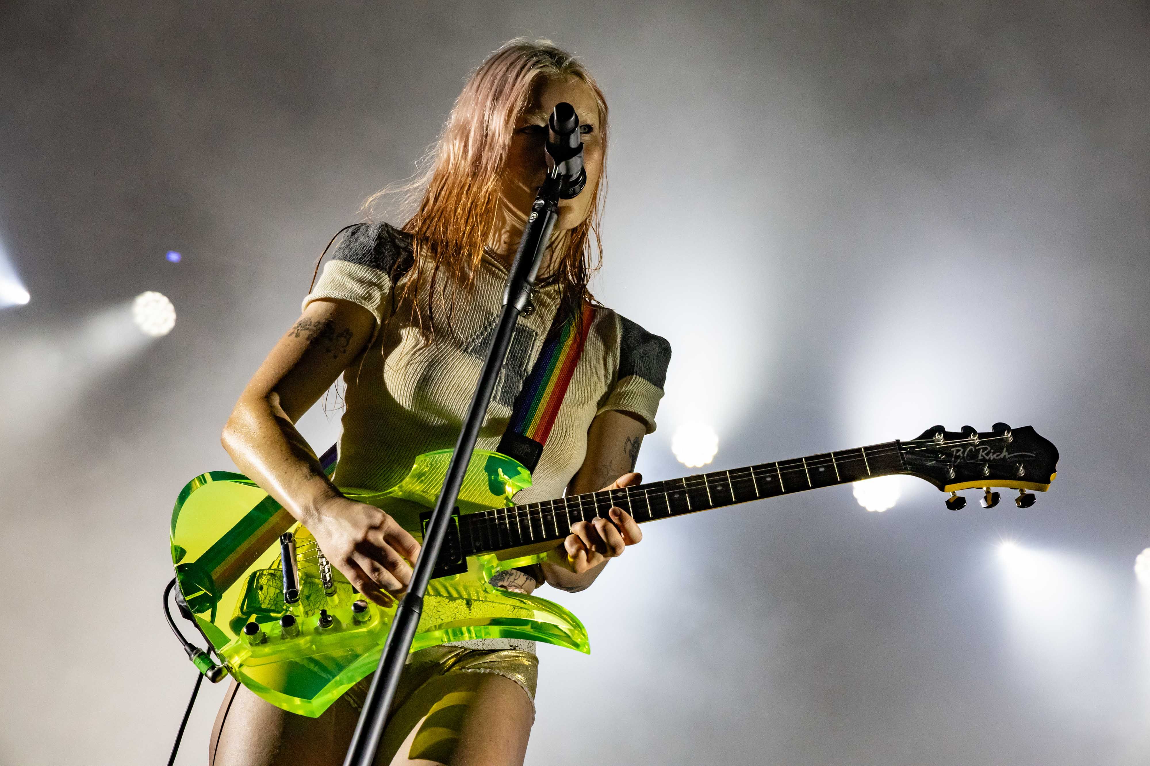 The frontwoman from Wet Leg plays her transparent green guitar and sings, backlit by white
