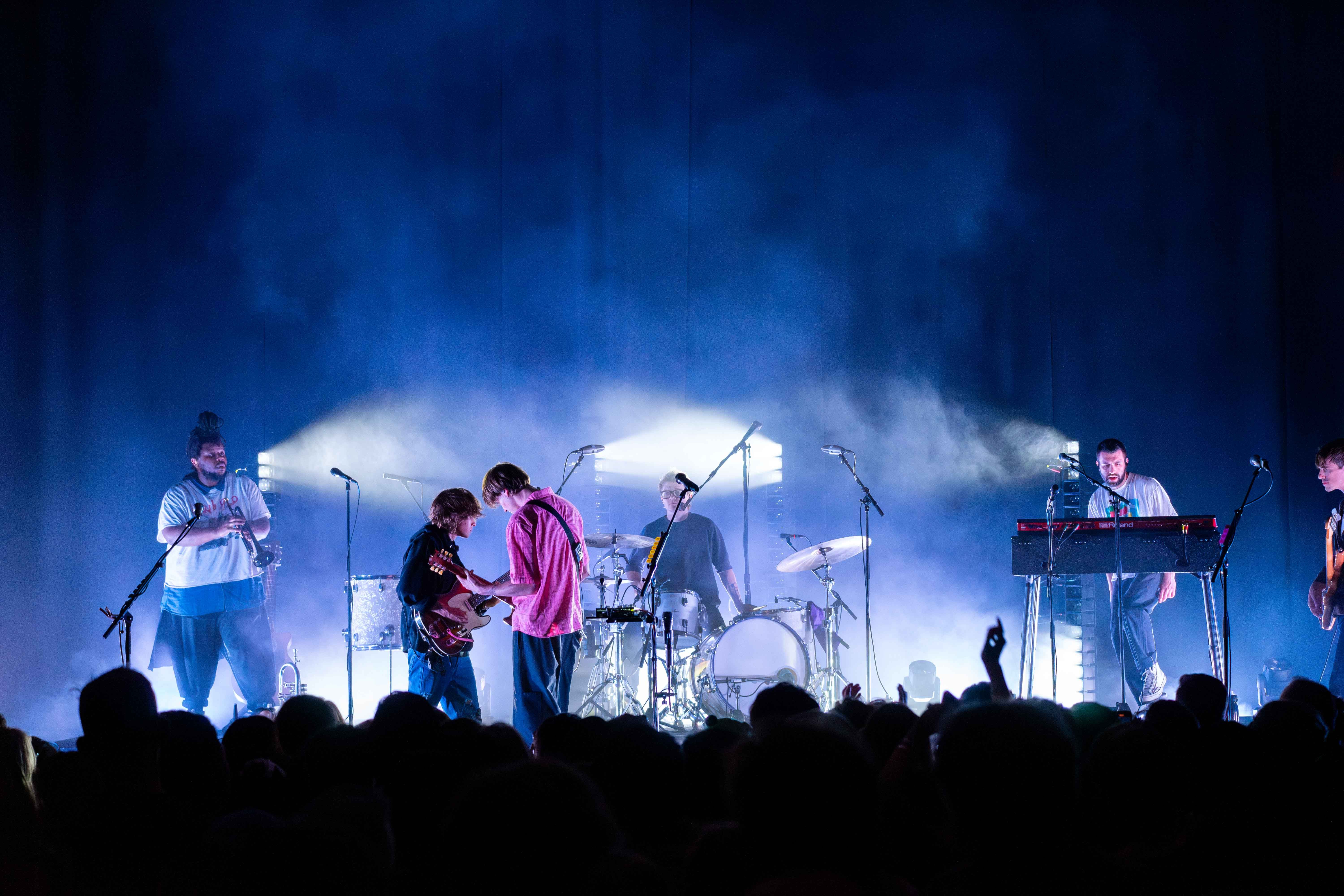 Hippo Campus are on stage at the Vogue Theatre lit in blue and white with mist.