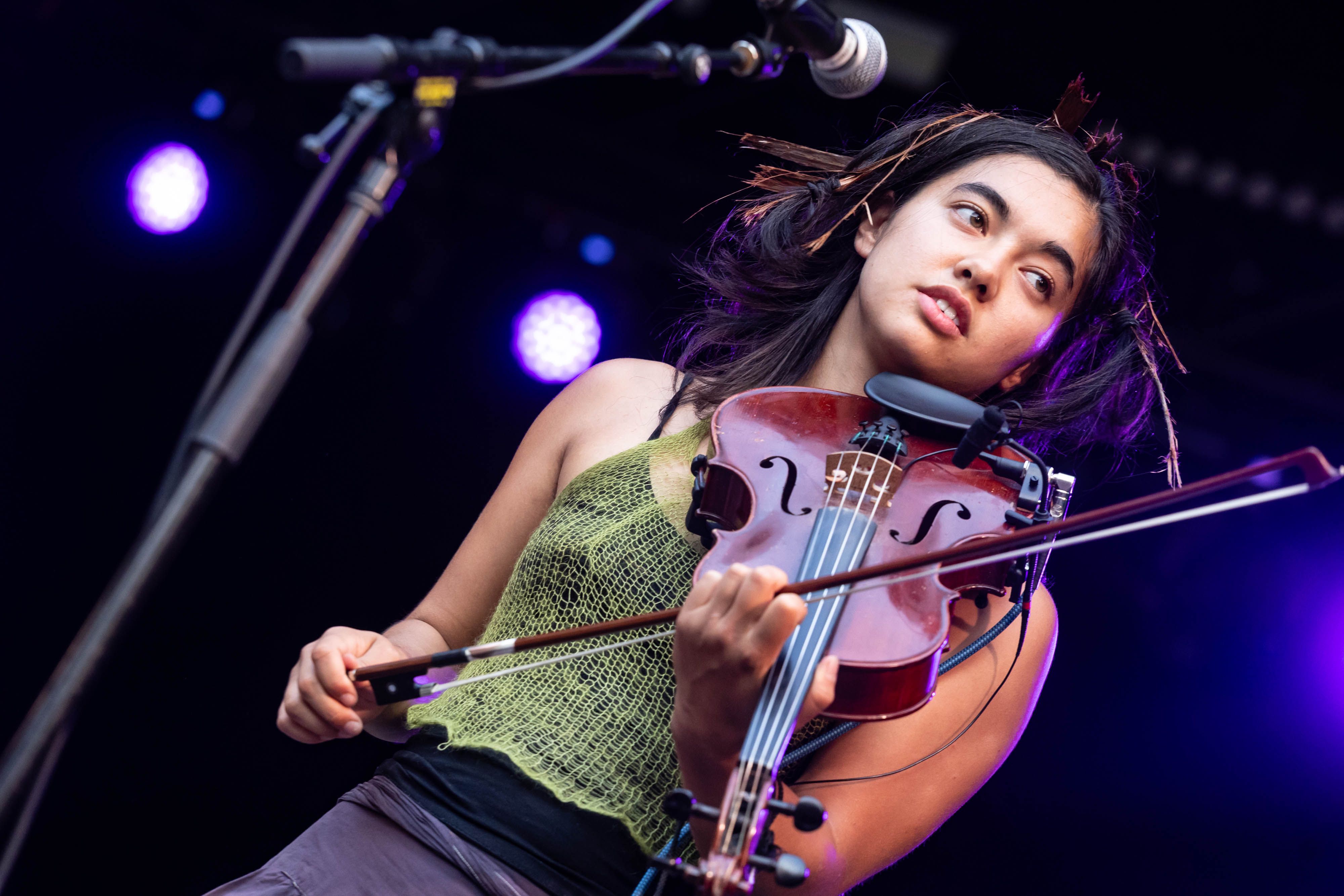 The backing violinist is looking to frame right as her hair dangles with bits of bark in it