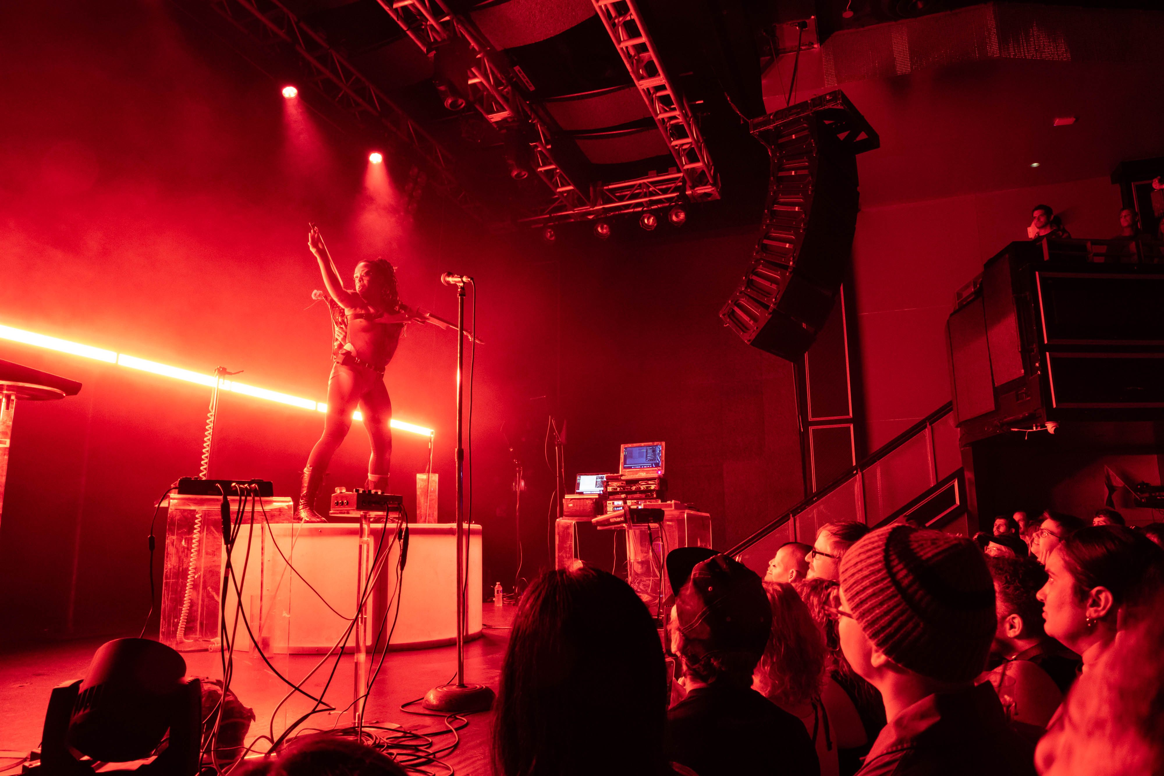 Sudan Archives is on her podium on the stage, tucking her bow into the sling on her back like a sword