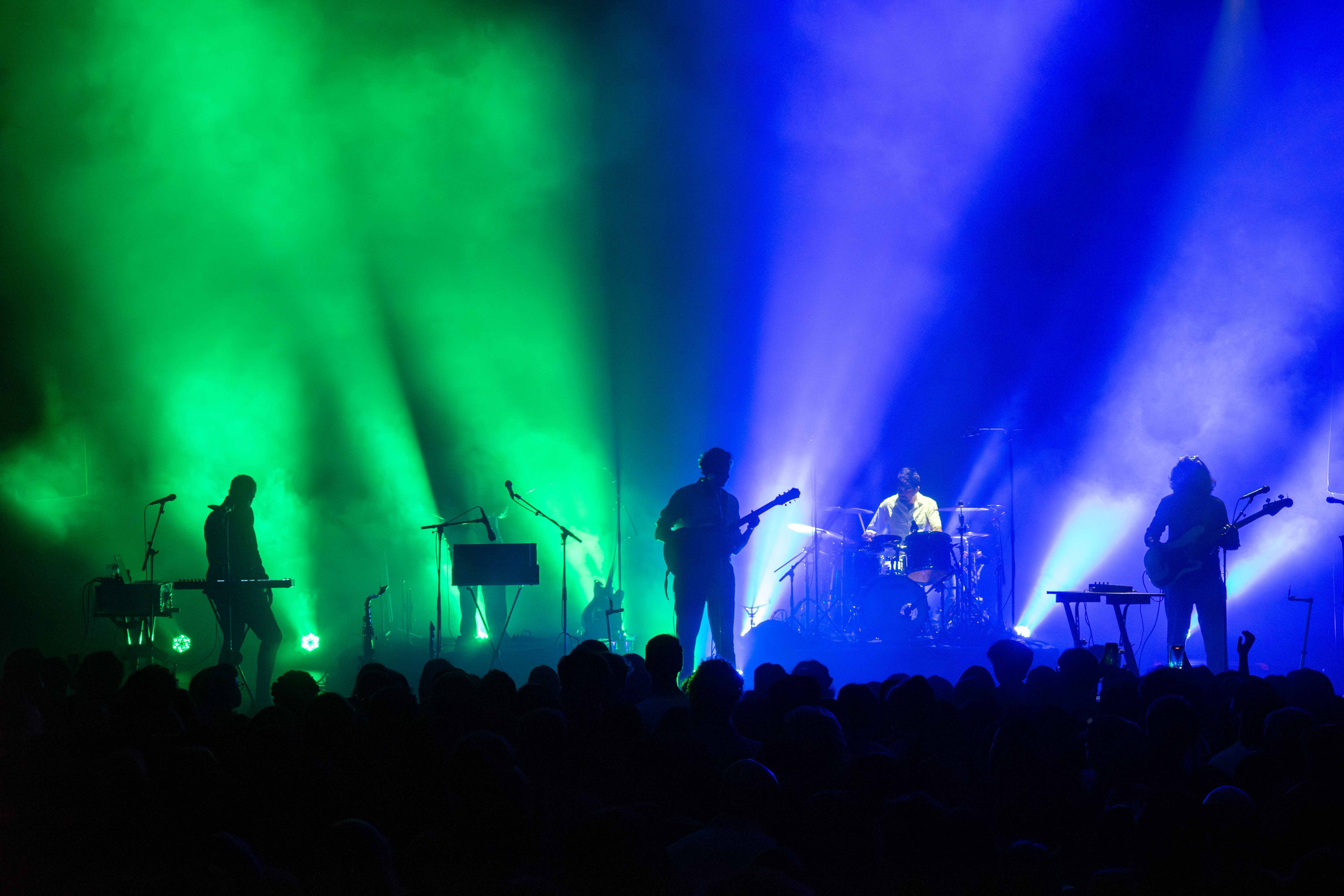 Blue and green light backlight Peter Cat Recording Co. as they play on the stage at the Vogue Theatre