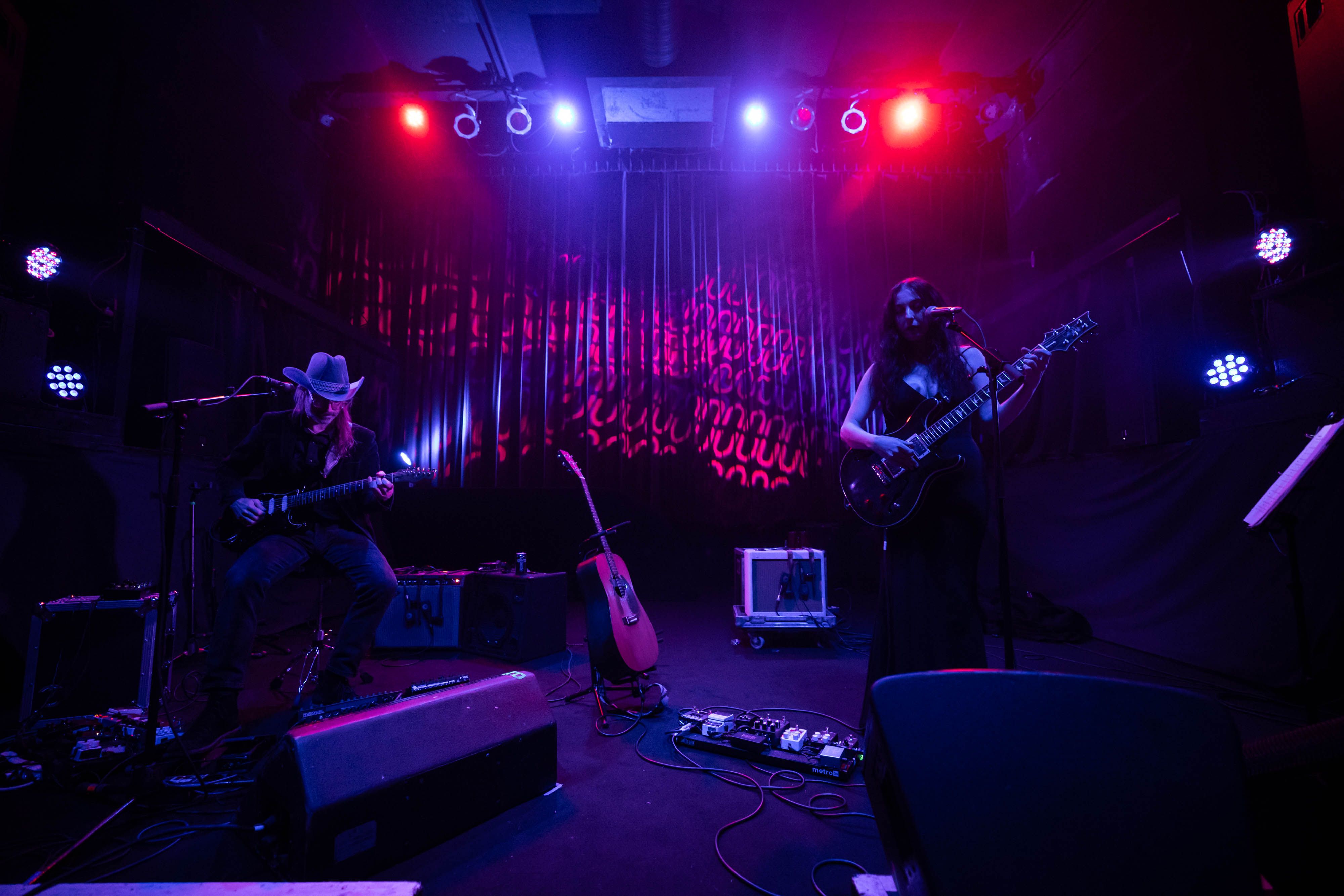 Marissa Nadler is playing guitar on the stage at the Fox lit in blue and backlit by red circles