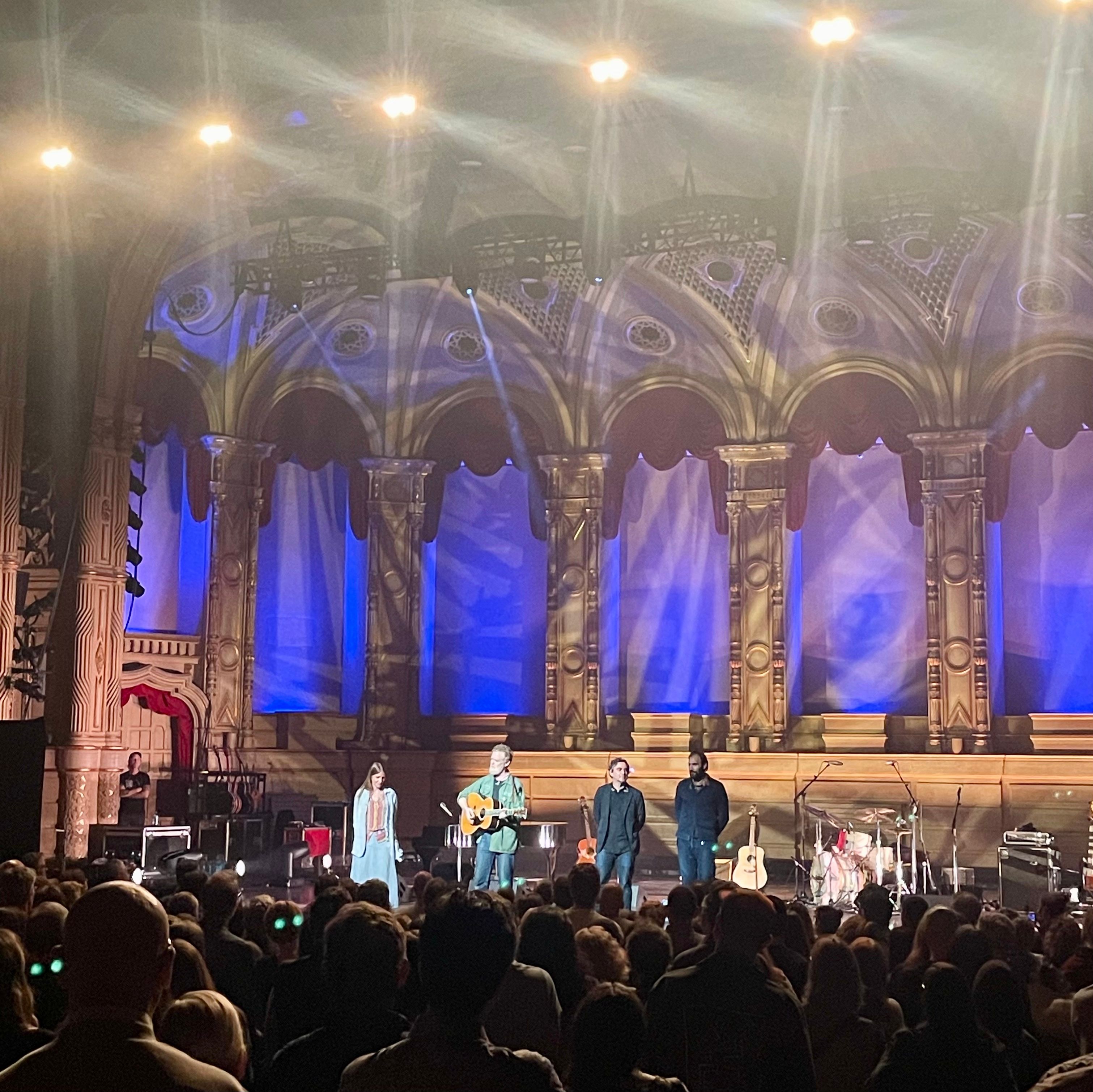 Lights shine on stage where Glen Hansard and Markéta Irglová, along with their bassist and drummer, stand in front of the crowd.