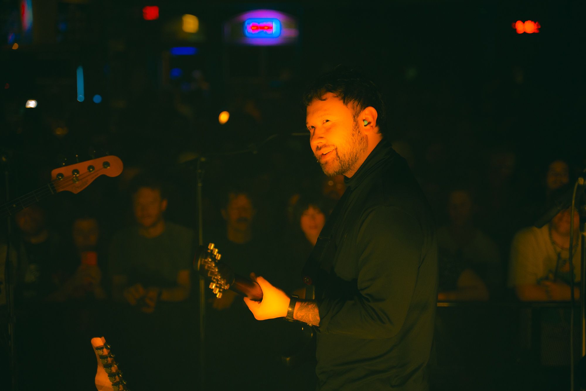 Unknown Mortal Orchestra frontman Ruban Nielson smiles at bandmates with audience in background.