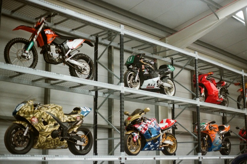 Motorcycles displayed on industrial shelving units in a warehouse