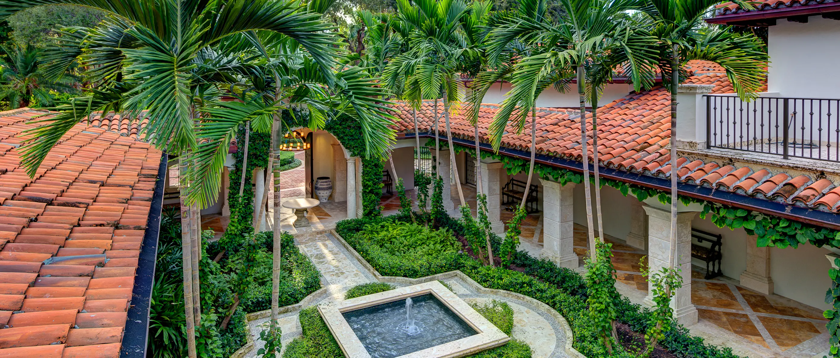 Second-floor balcony view overlooking lush interior courtyard with fountain and tropical landscaping