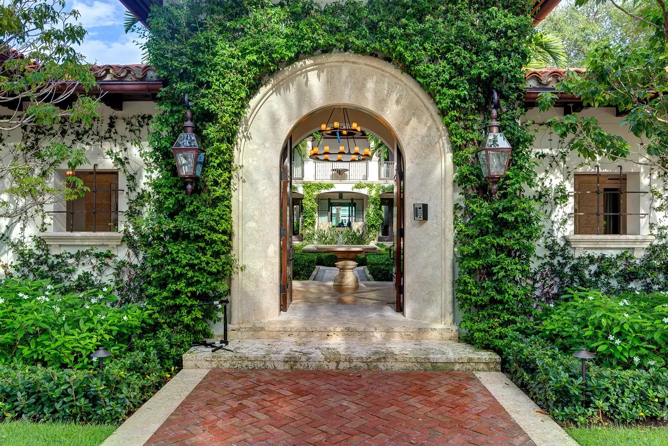 Grand stone archway entrance adorned with climbing ivy leading to lush private courtyard