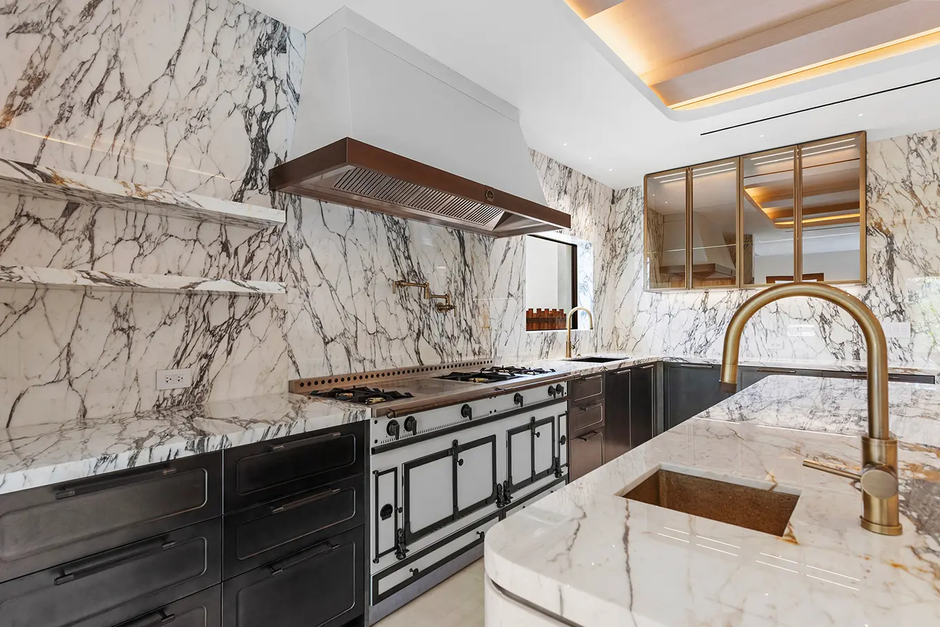 Luxurious gourmet kitchen with dramatic veined marble walls, professional La Cornue range, and brushed copper fixtures