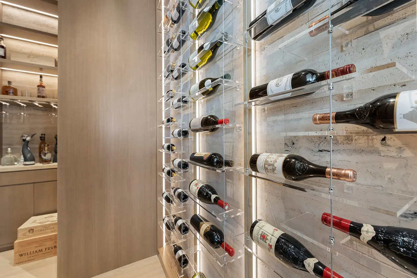 Climate-controlled glass wine cellar with modern acrylic display featuring premium wine collection and LED lighting