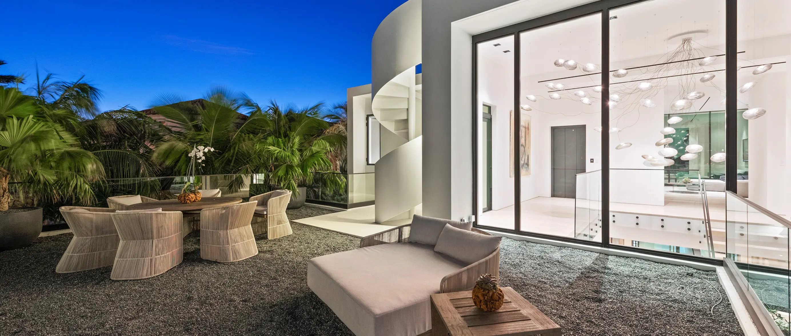 Covered outdoor lounge area with modern statement chandelier and views of second-floor landing