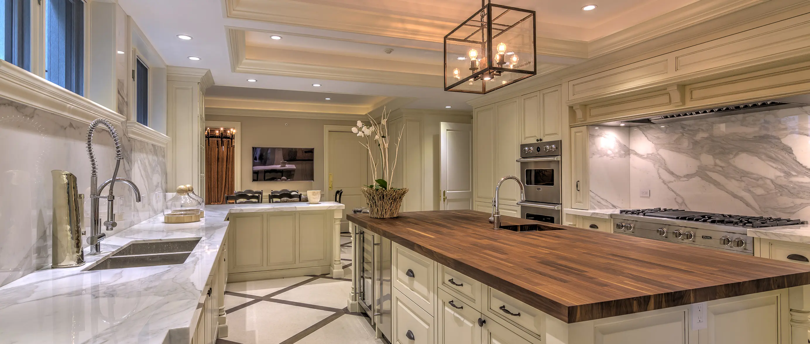 Gourmet kitchen with stunning butcher block island, white marble countertops, cream cabinetry, and coffered ceiling