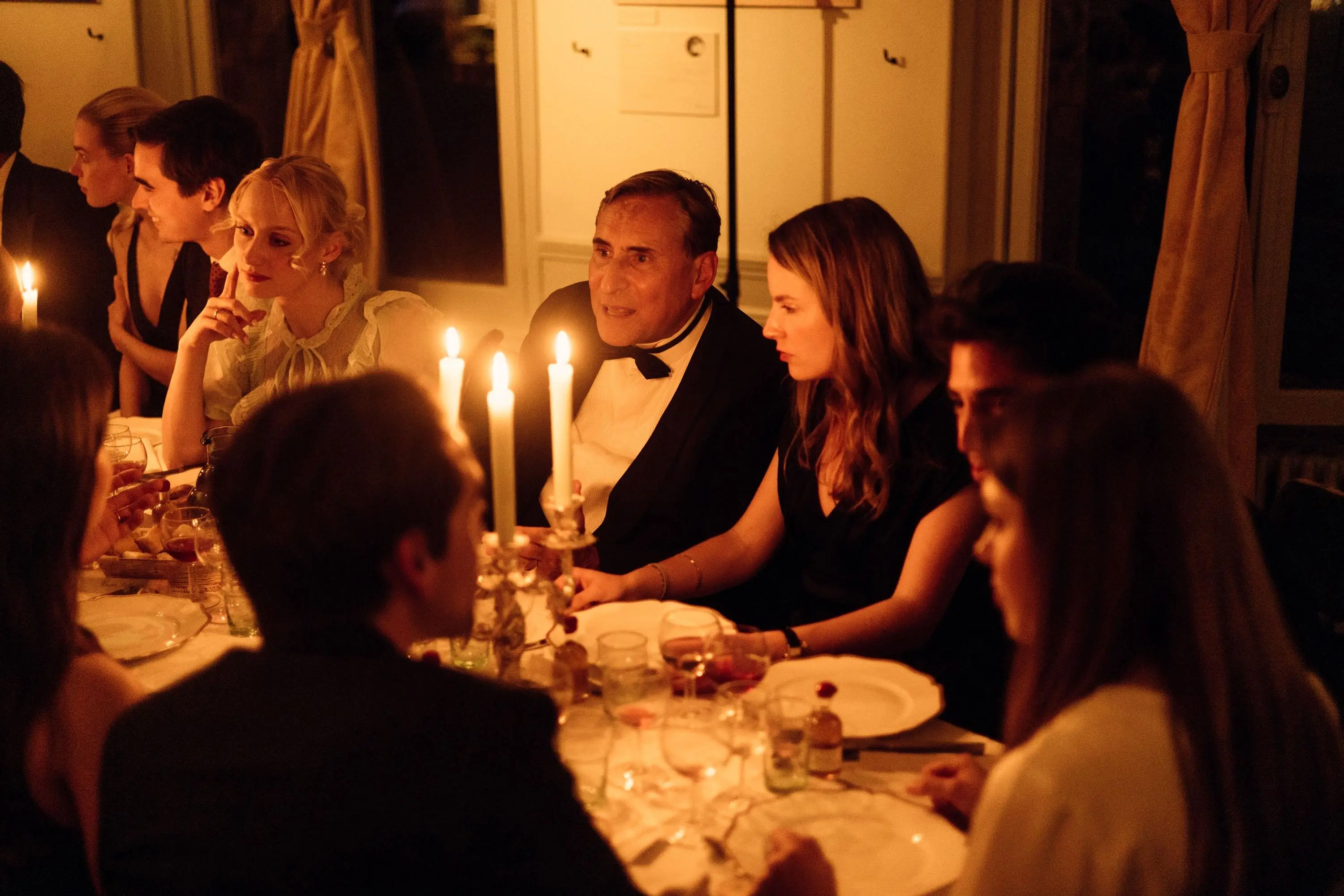 Un couple s'embrassant lors d'une soirée élégante, avec des effets de lumière flous et une étole en fourrure blanche.