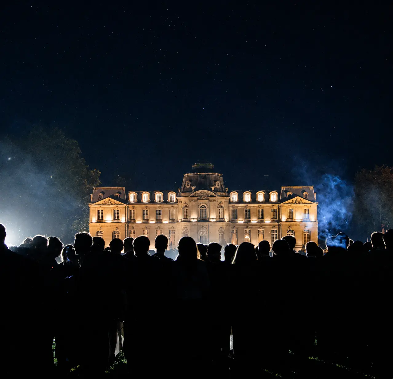 Une membre du club en robe blanche danse avec un verre de champagne à la main.