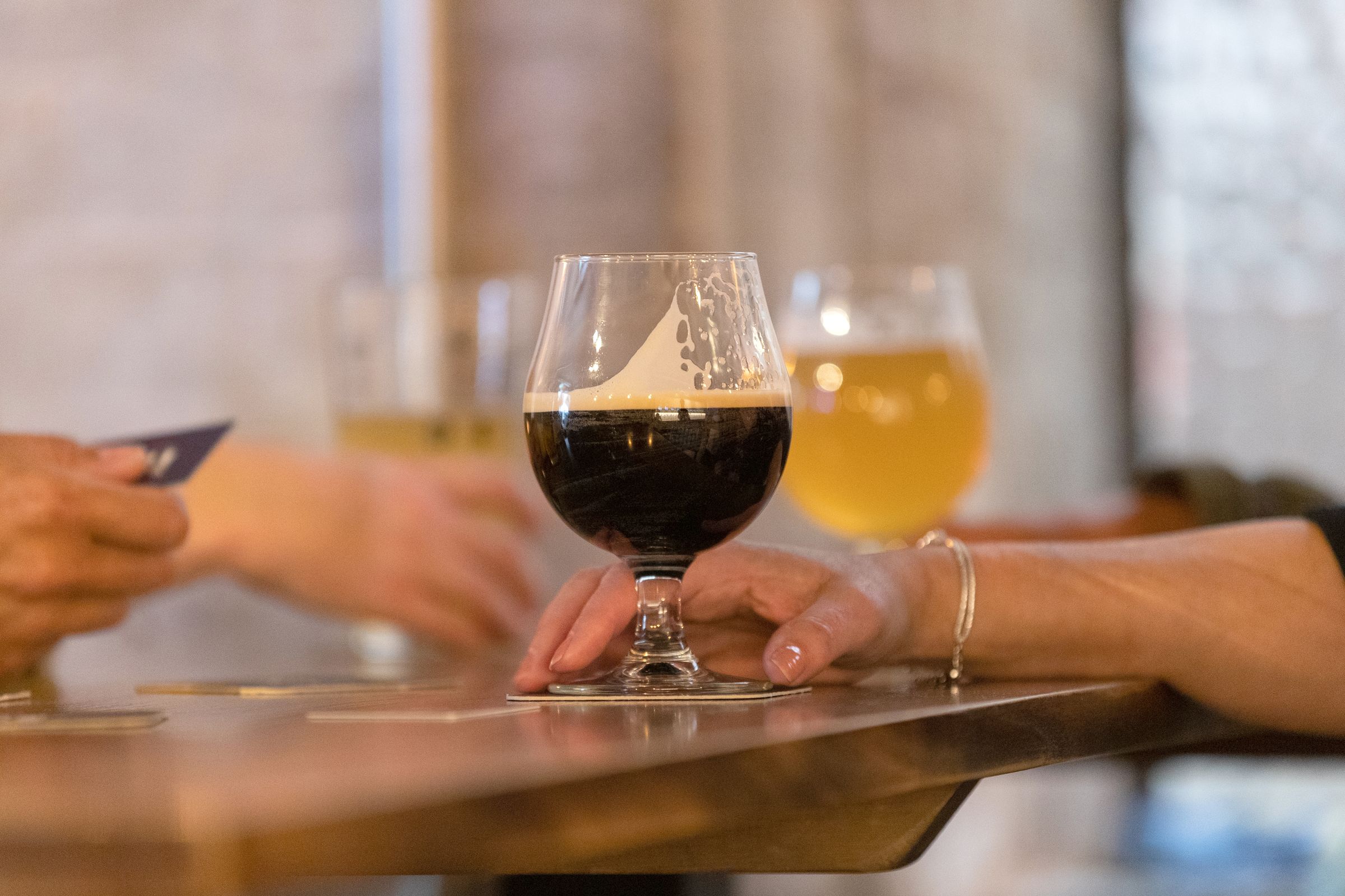 A hand holding a glass of ale in a pub