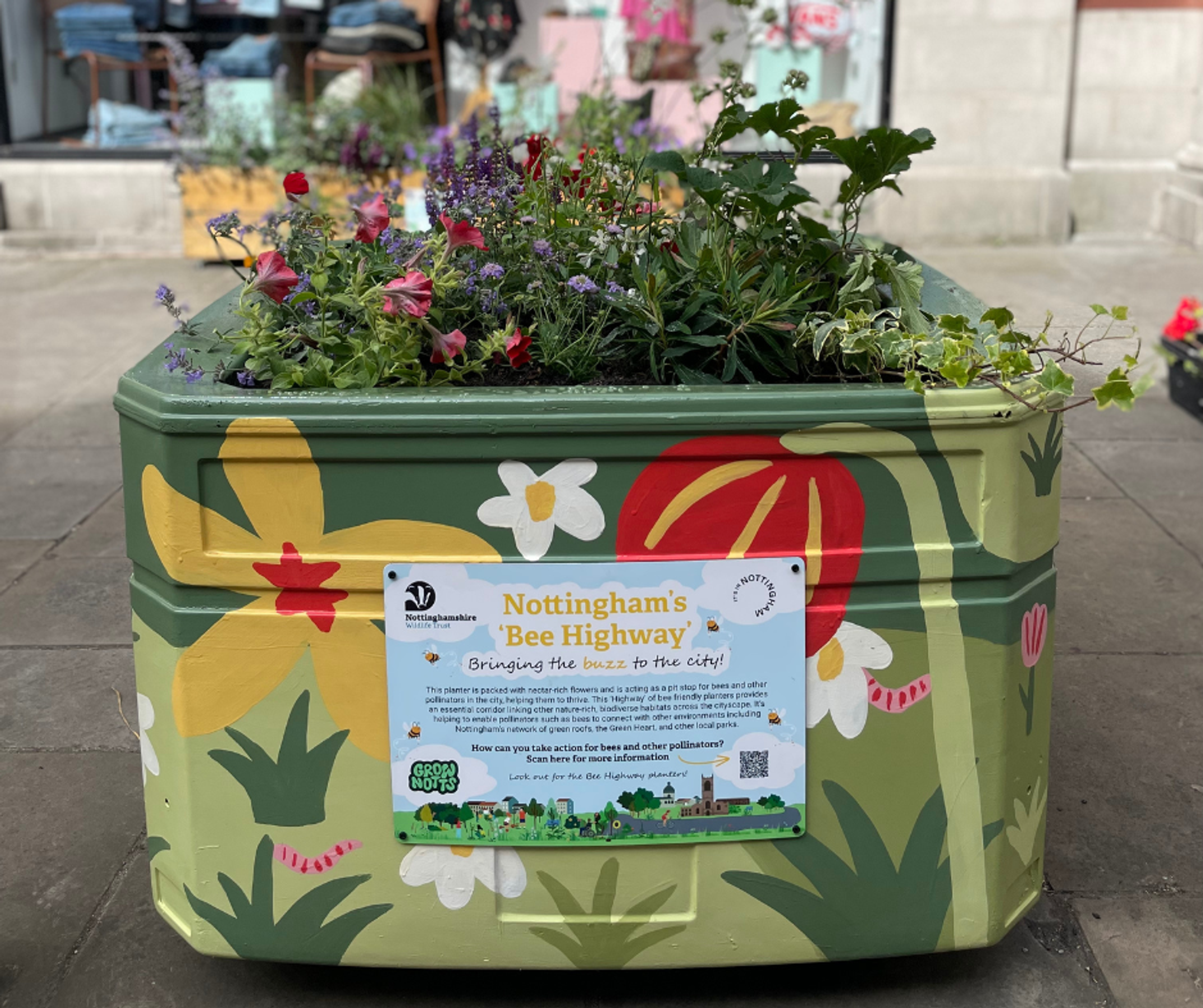 A coloured planter full of plants and a sign reading Nottingham's 'Bee Highway: bringing the buzz to the city!'