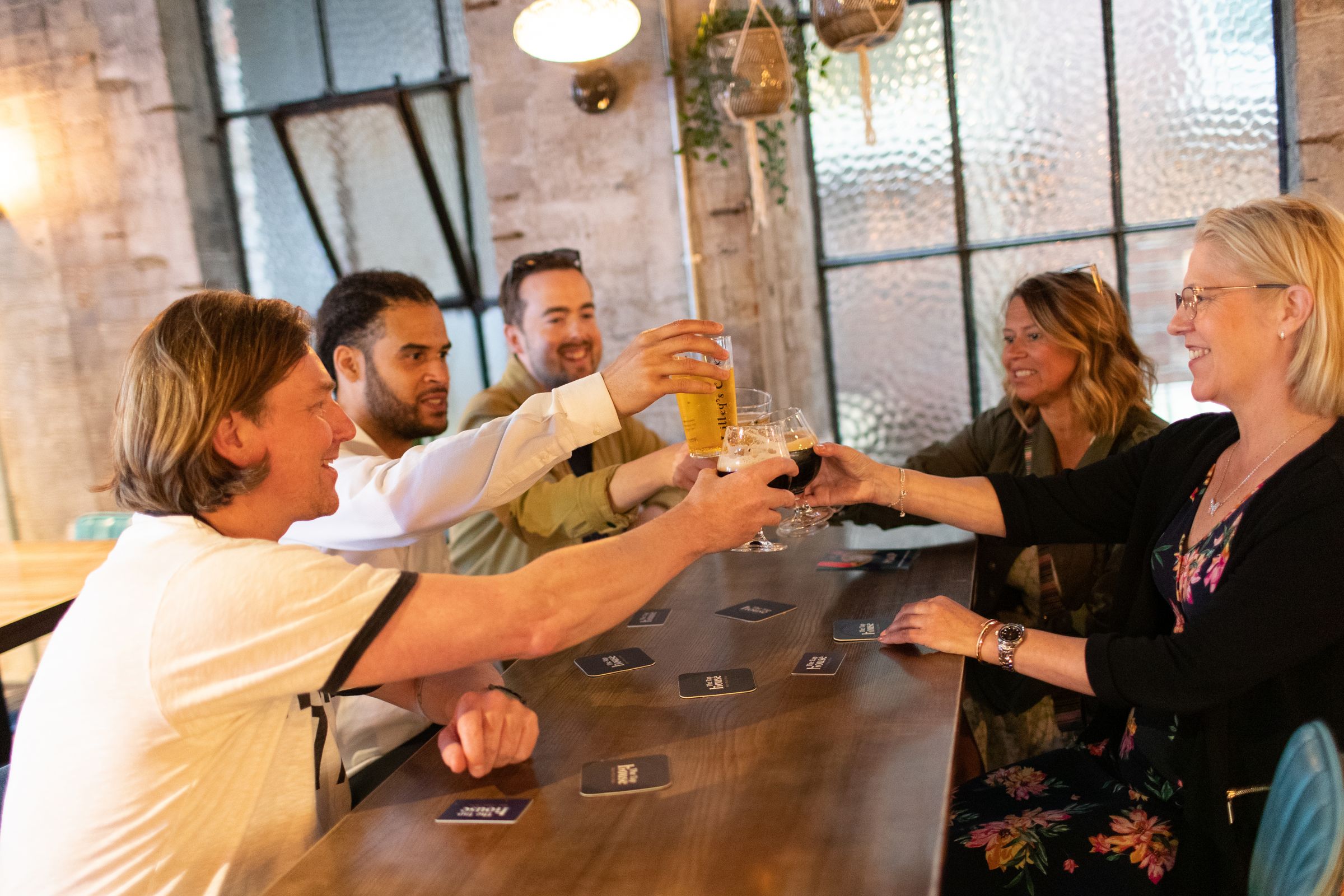 A group of friends in a pub clinking glasses of beer