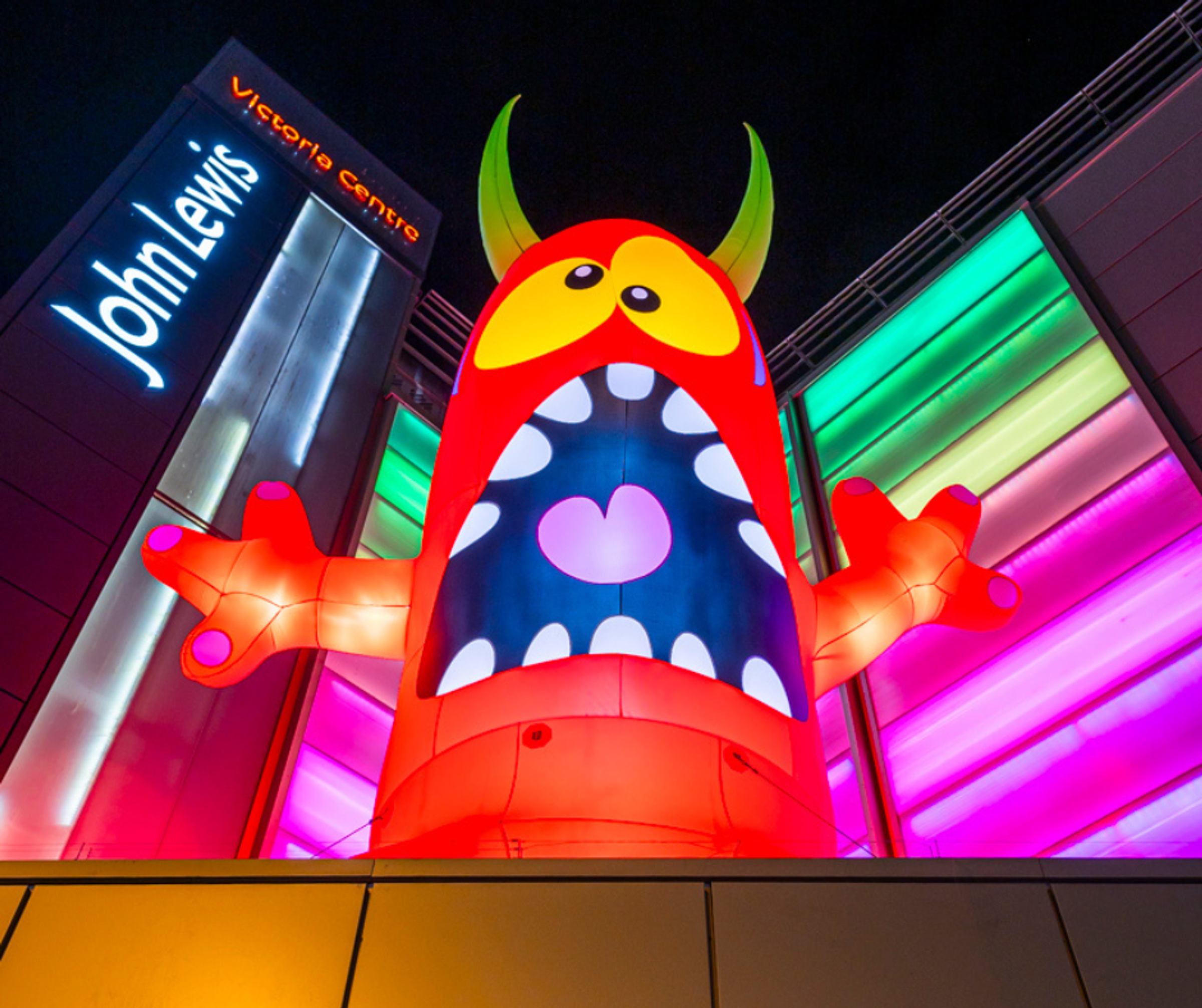 An inflatable halloween monster on the roof of Victoria Centre, Nottingham with coloured lights in the background