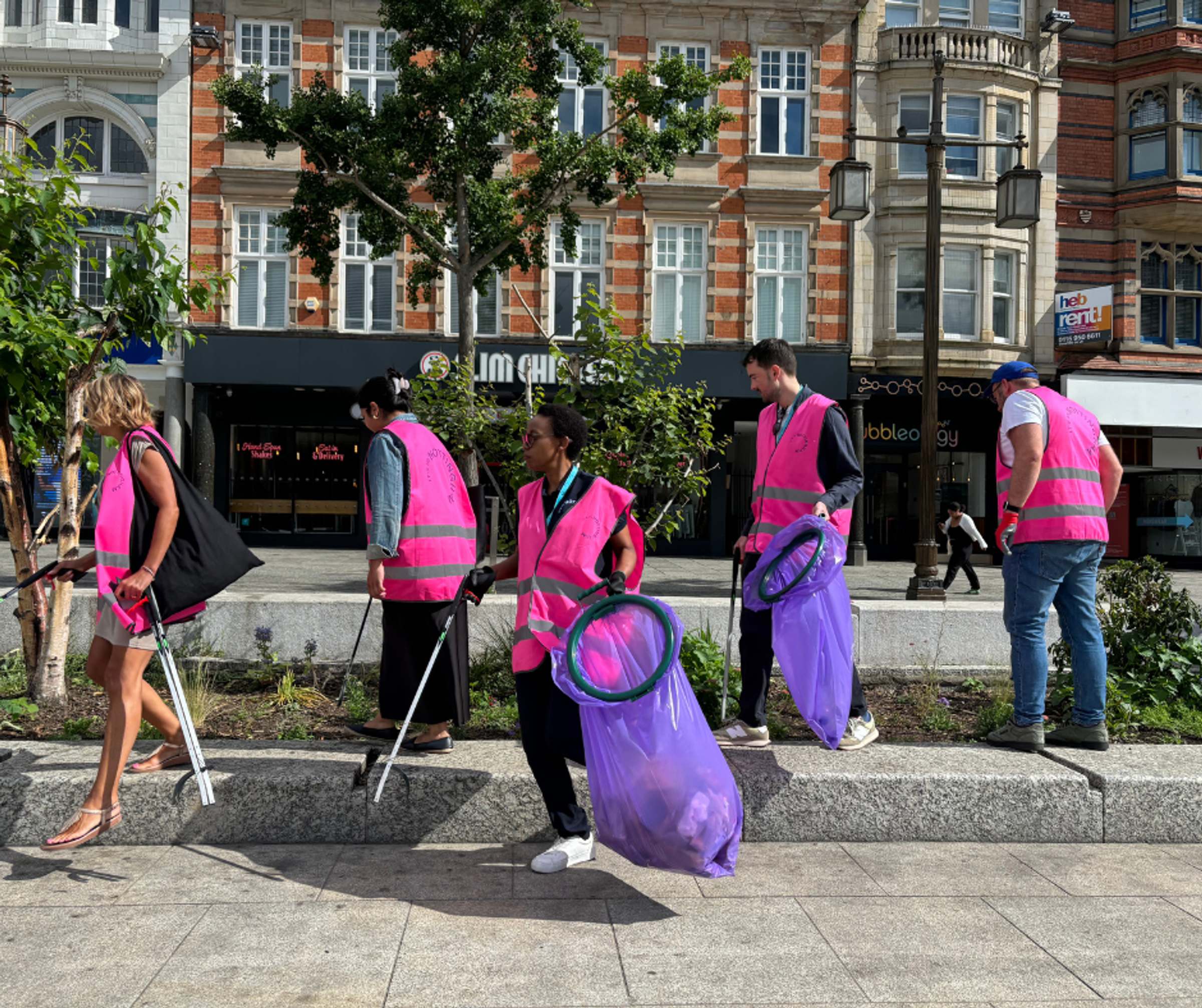 5 of the It's in Nottingham team picking litter on Old Market Square in the sunshine.