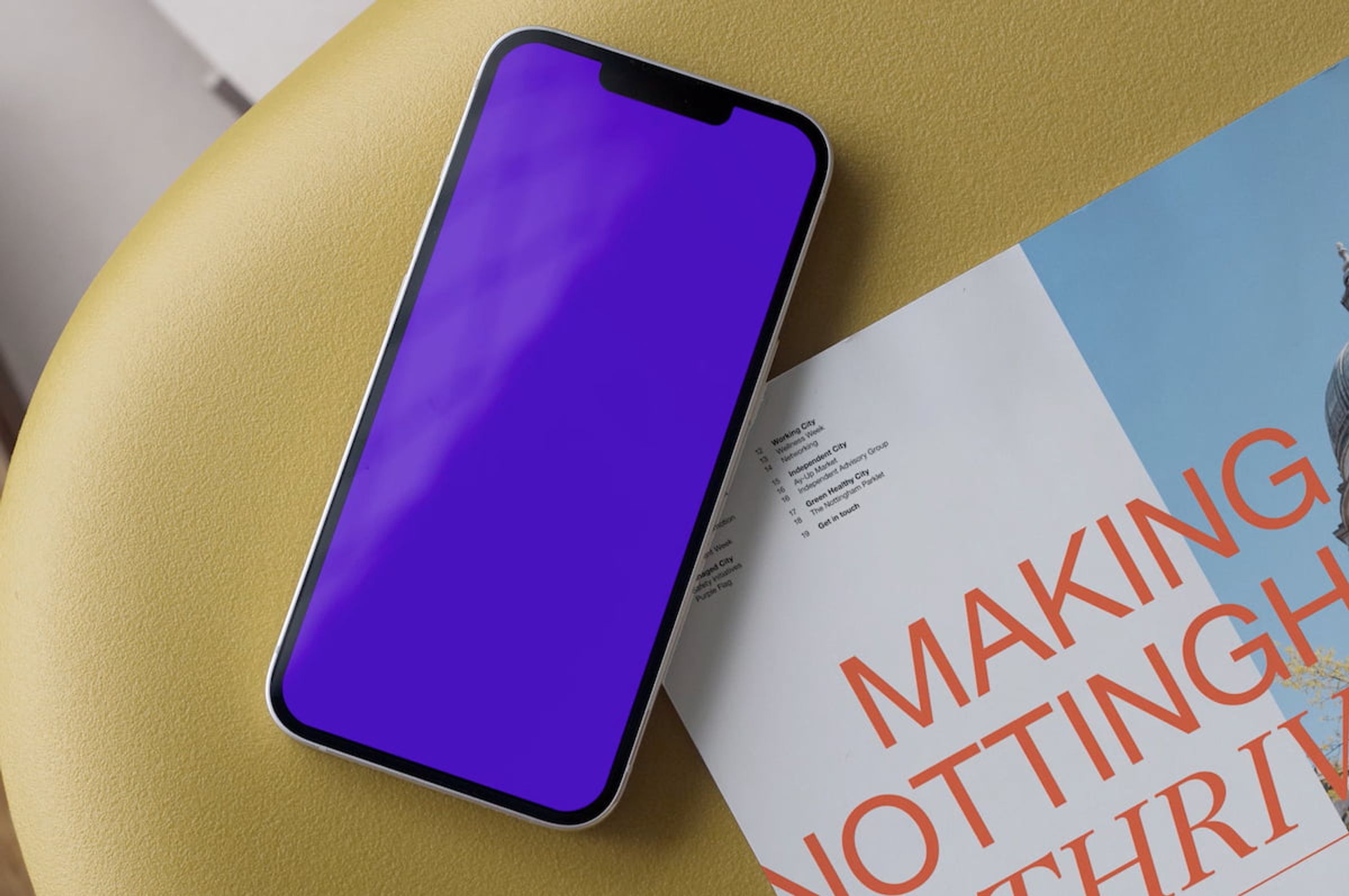 A phone with a purple screen laid on top of an It's in Nottingham brochure