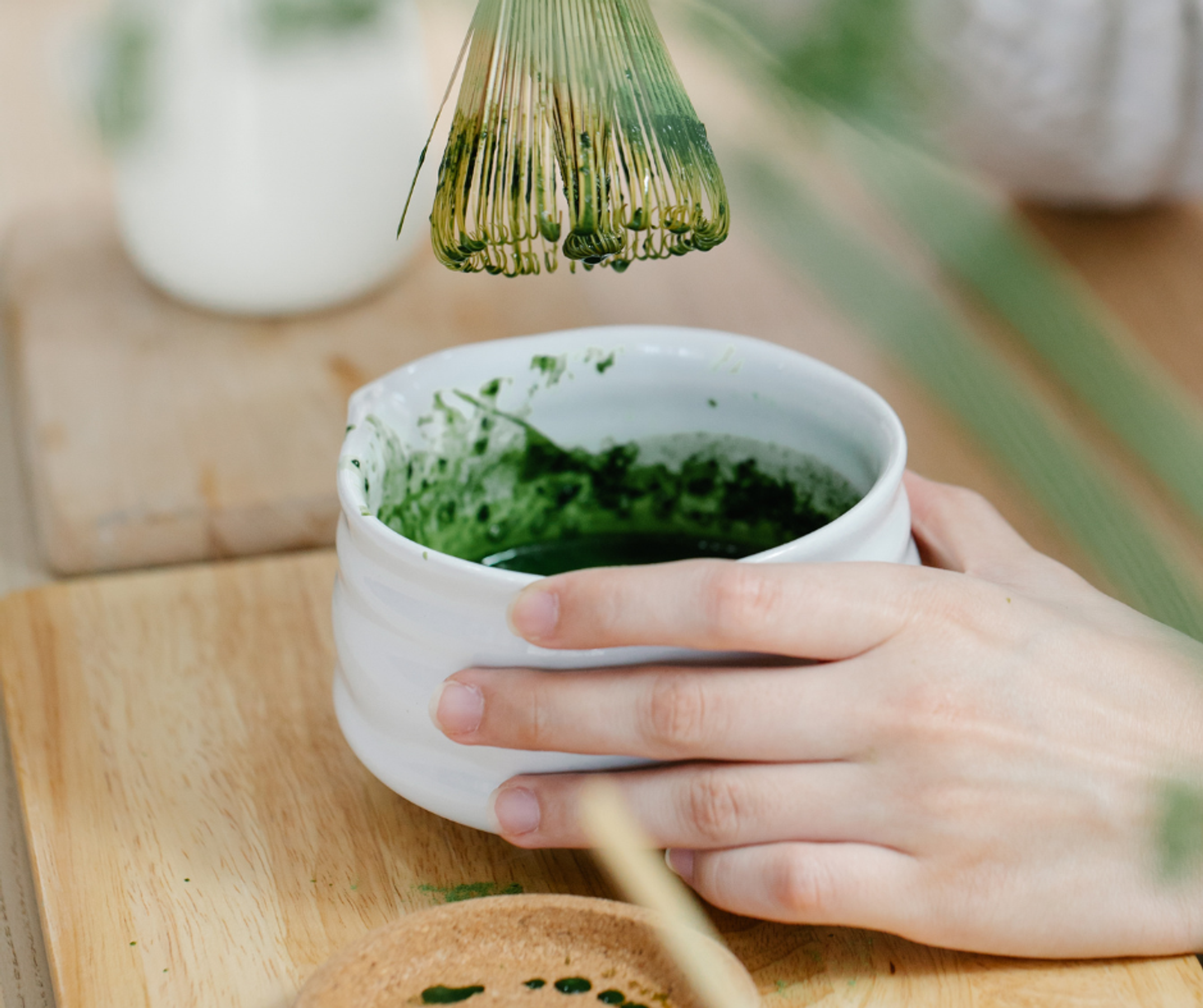 A hand of someone whisking matcha to make drinks
