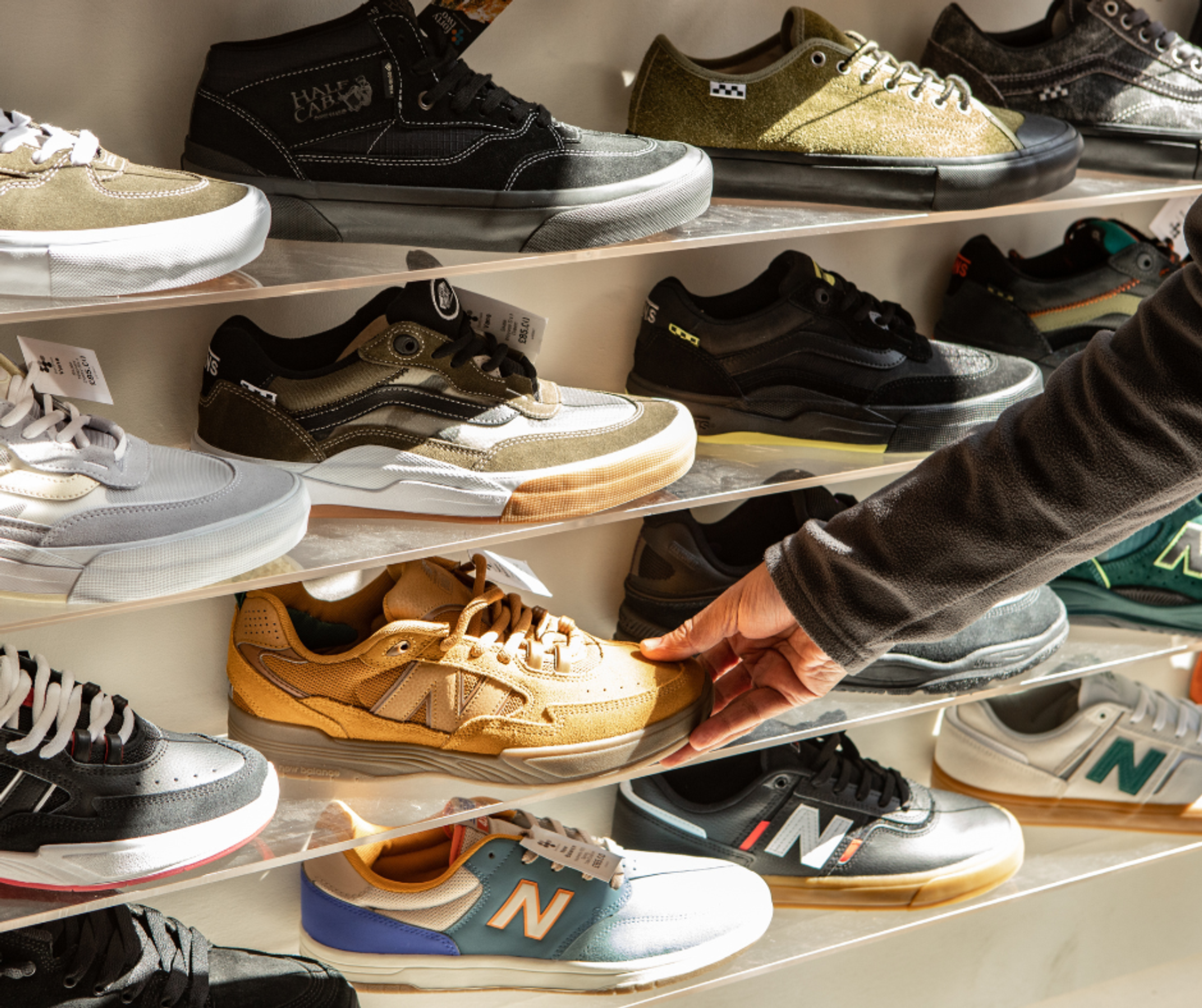 A hand reaching to pick up a trainer from an in-store display