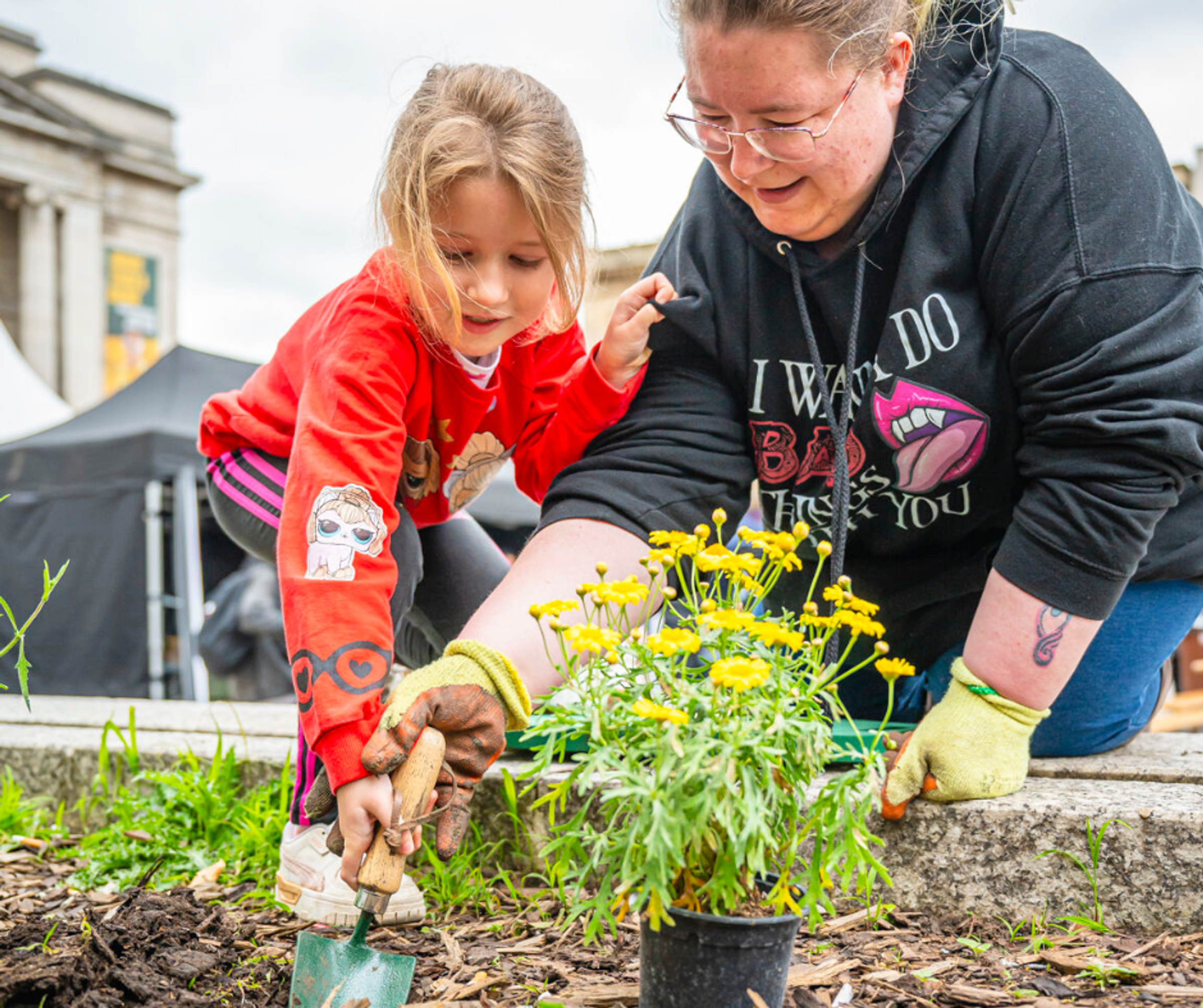 A young girl and woman planting a yellow plant at Old Market Square, Nottingham