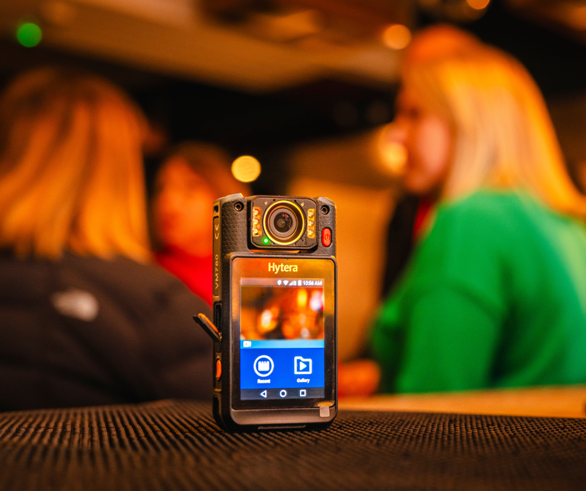 A bodycam on a table with people at a bar on a night out blurred in the background.