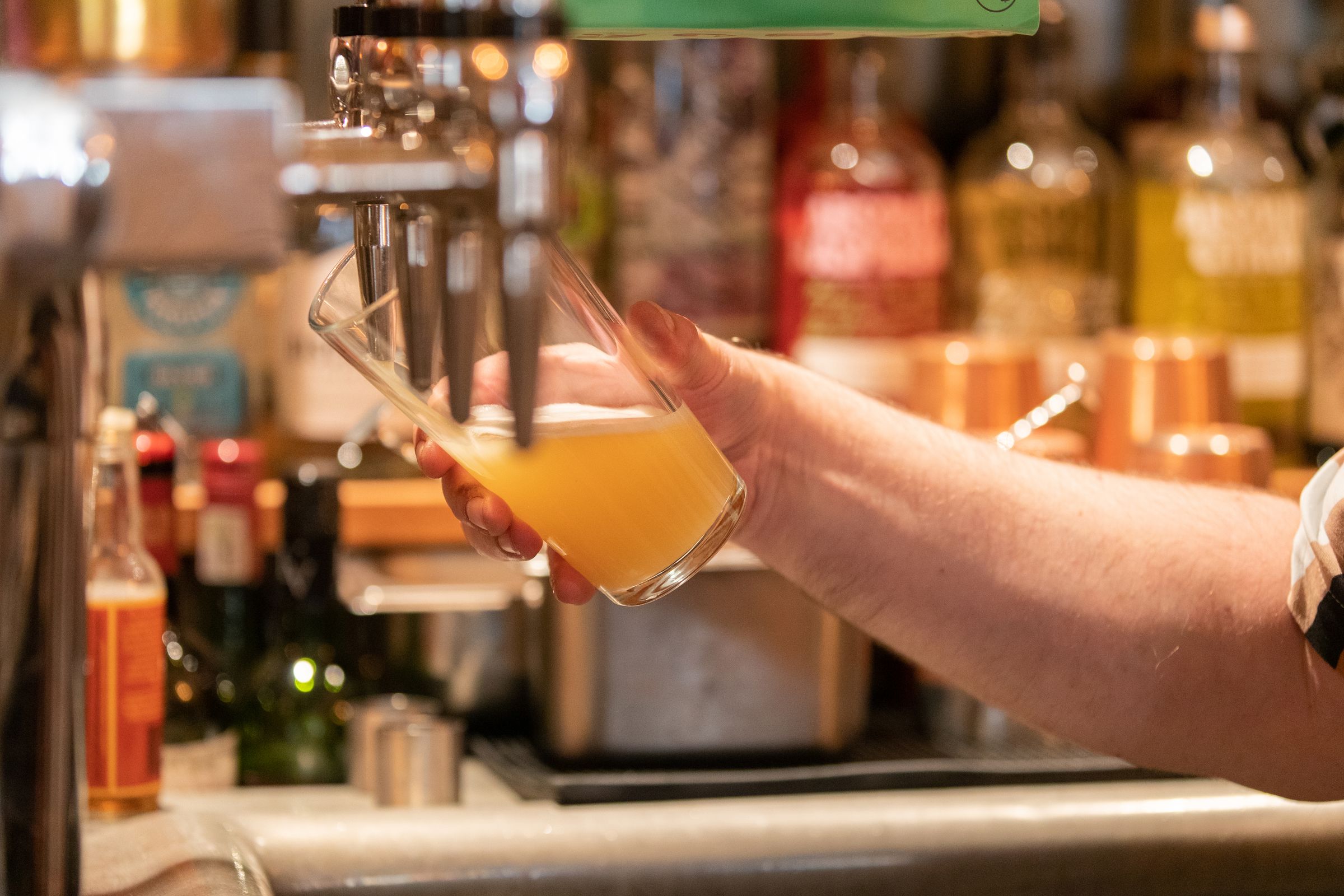 A close up of a bartender pulling a pint