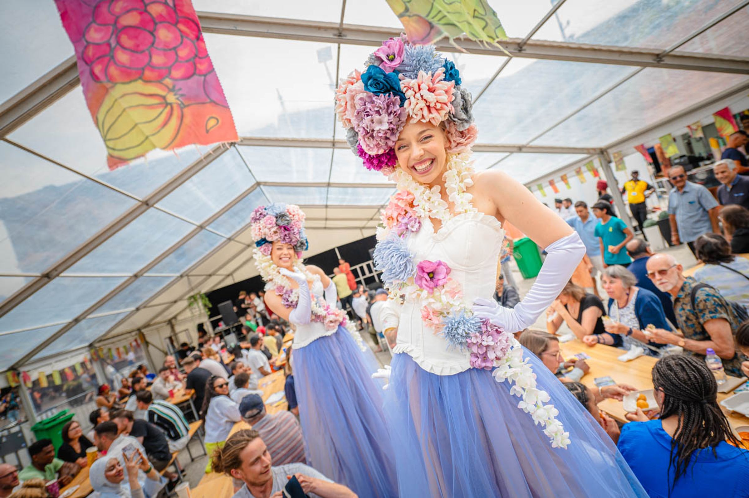 Two female entertainers at Ay Up Market, Nottingham wearing stilts, long skirts and flowers as wigs