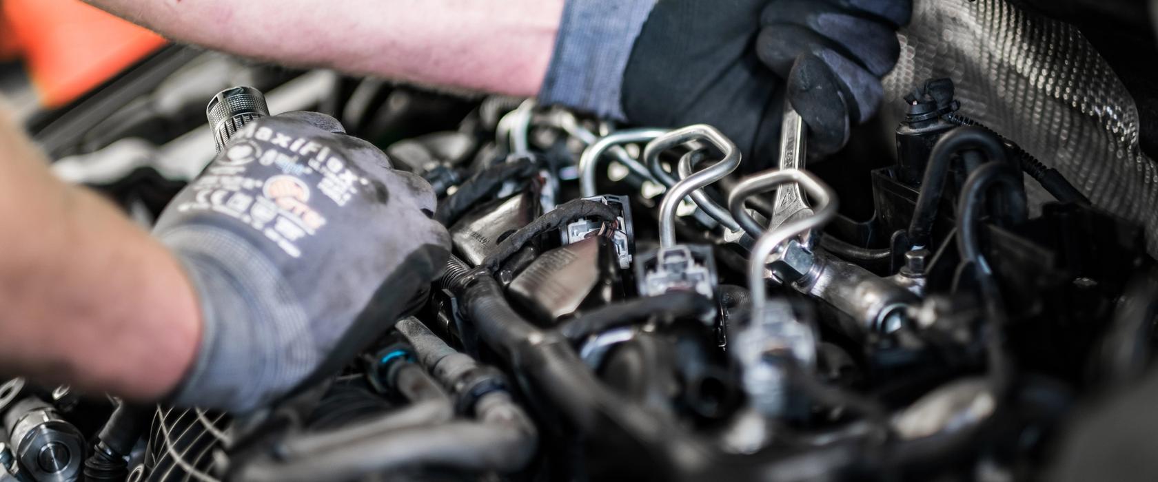 Våre dyktige mekanikere tar godt vare på bilen din En mekaniker som skrur på motoren i en bil