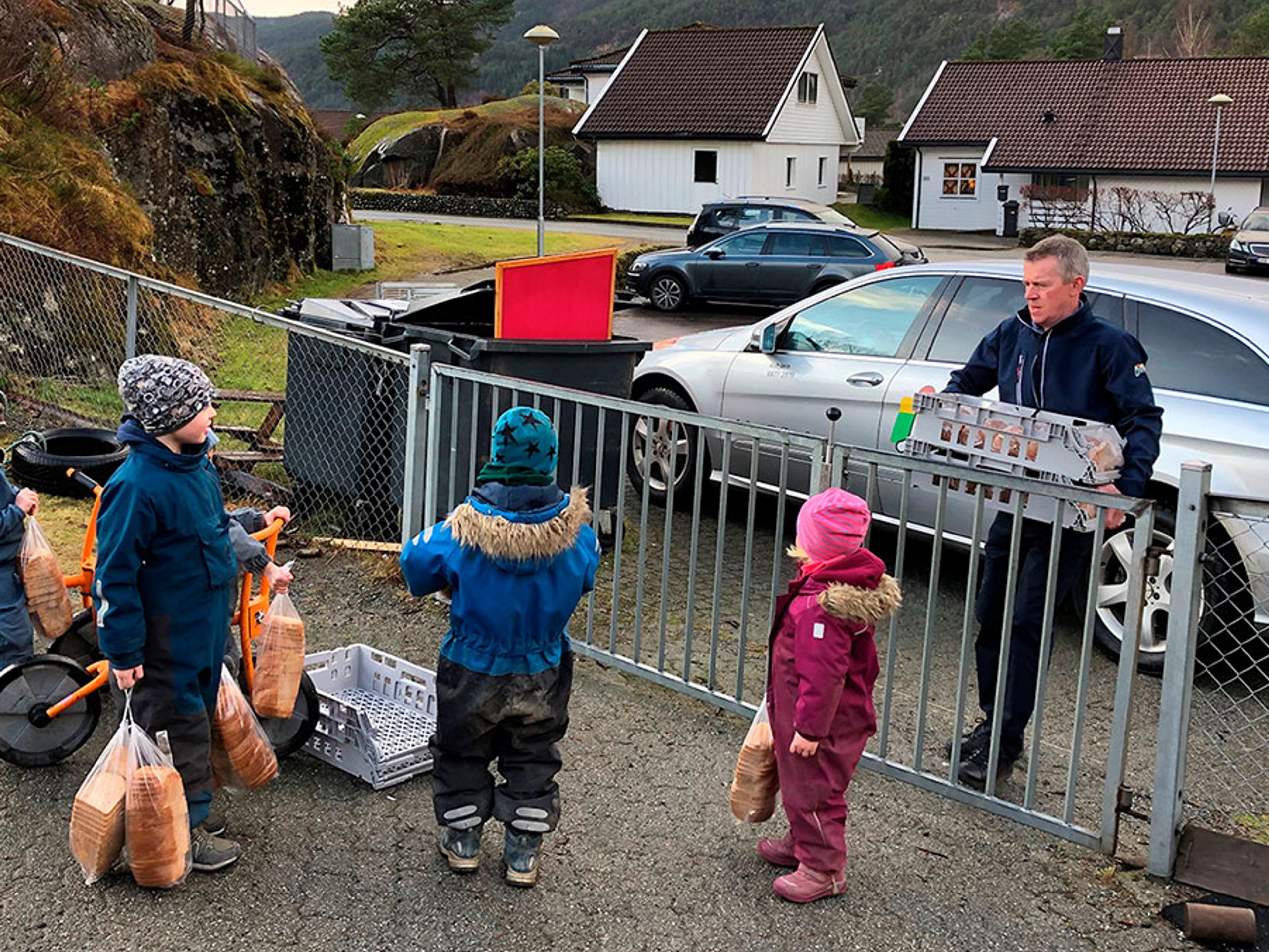Mann ved en port og barnehagebarn