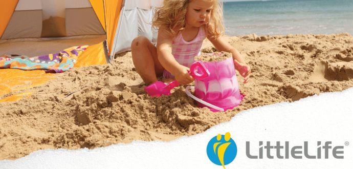 Little girl at the beach filling a bucket up with sand with an orange tent behind her