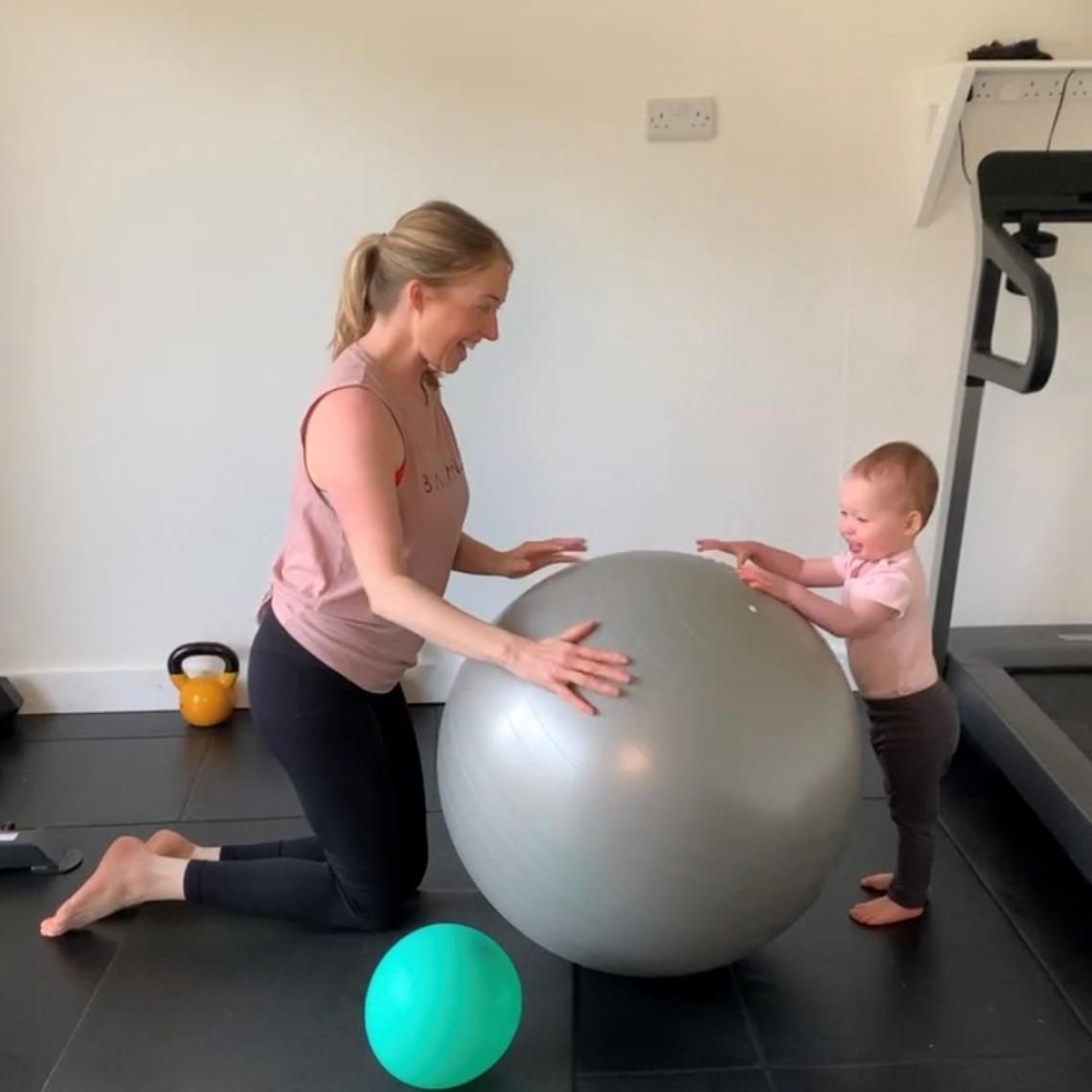 Woman working out and playing with an exercise ball with her child