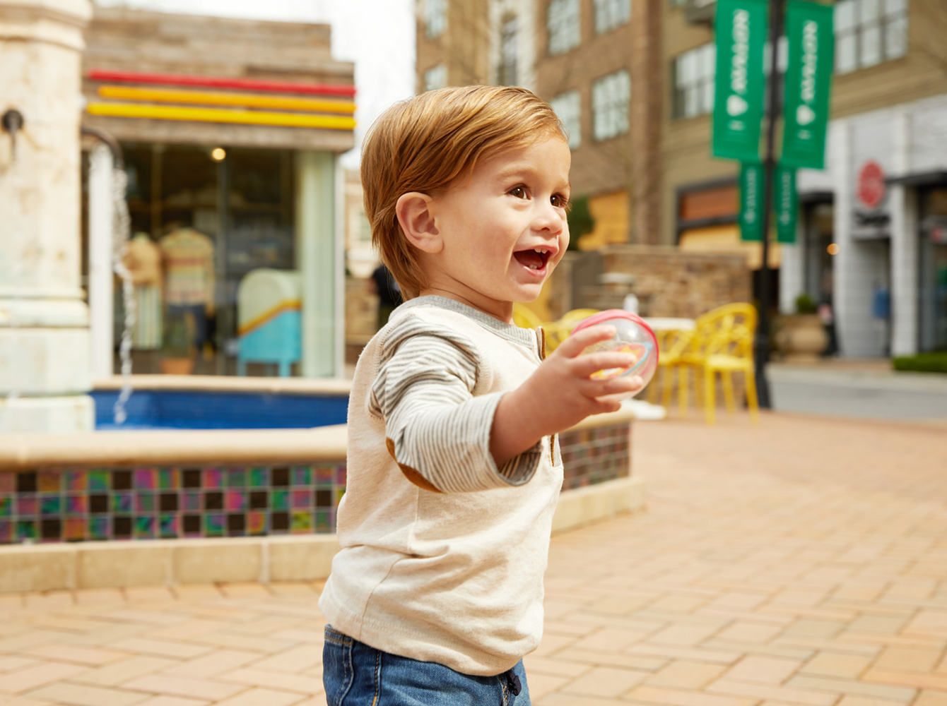 A young boy smiling while holding a toy in his hand.