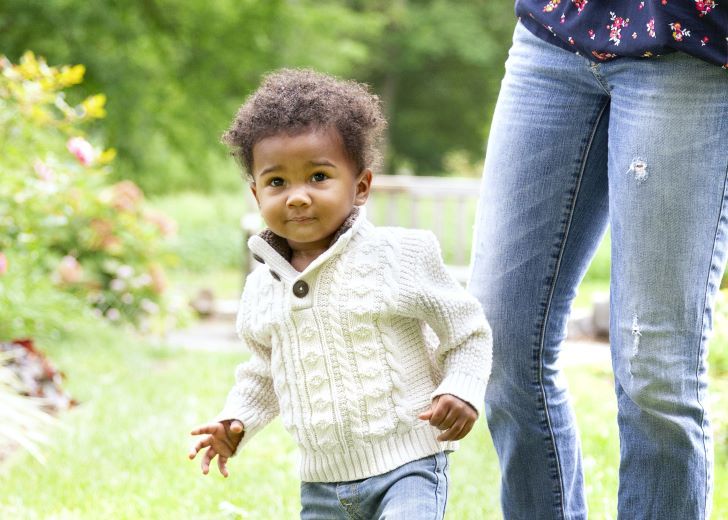 Ein kleiner Junge im Garten neben einer Frau