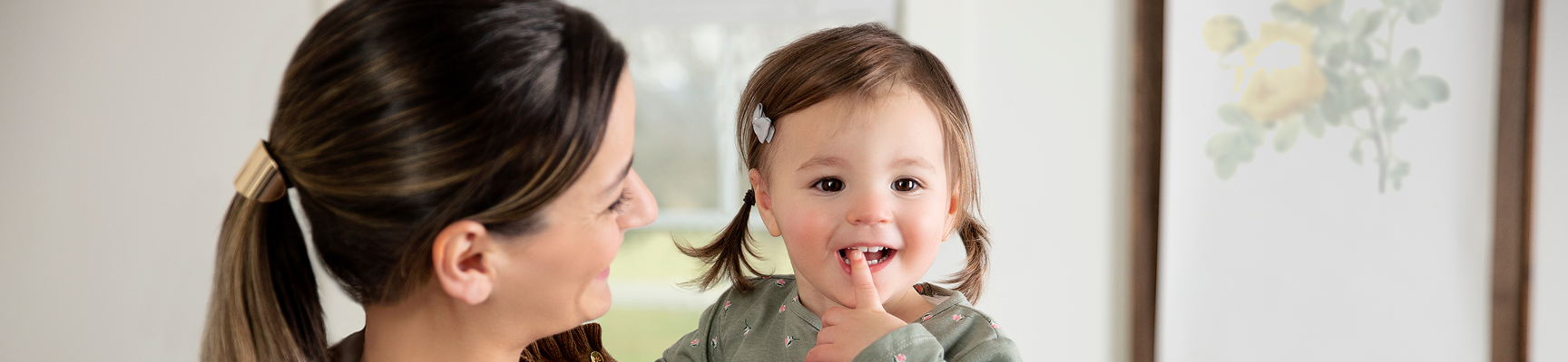 Smiling mother holding a happy toddler in her arms.
