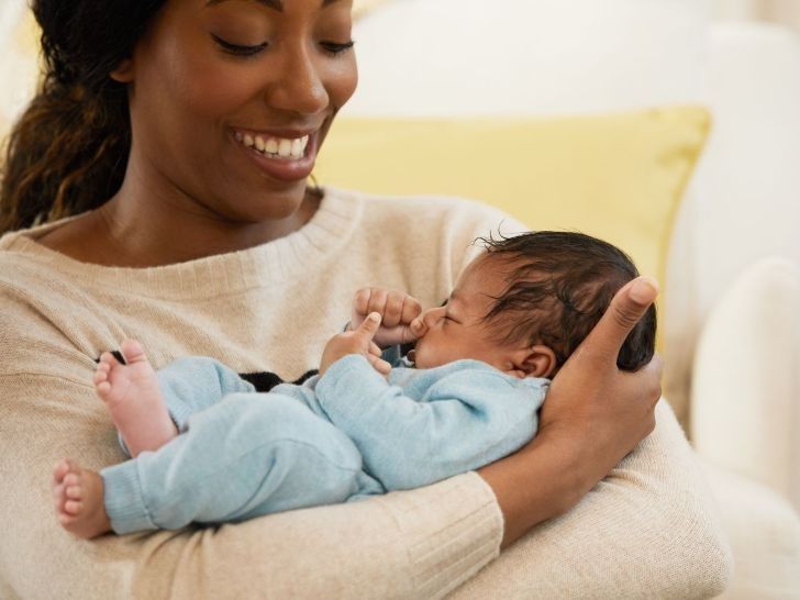 Une femme tient un petit bébé dans ses bras et lui sourit.