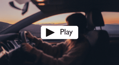A side view of a woman driving a car from within the vehicle and a sunset in the background. 
