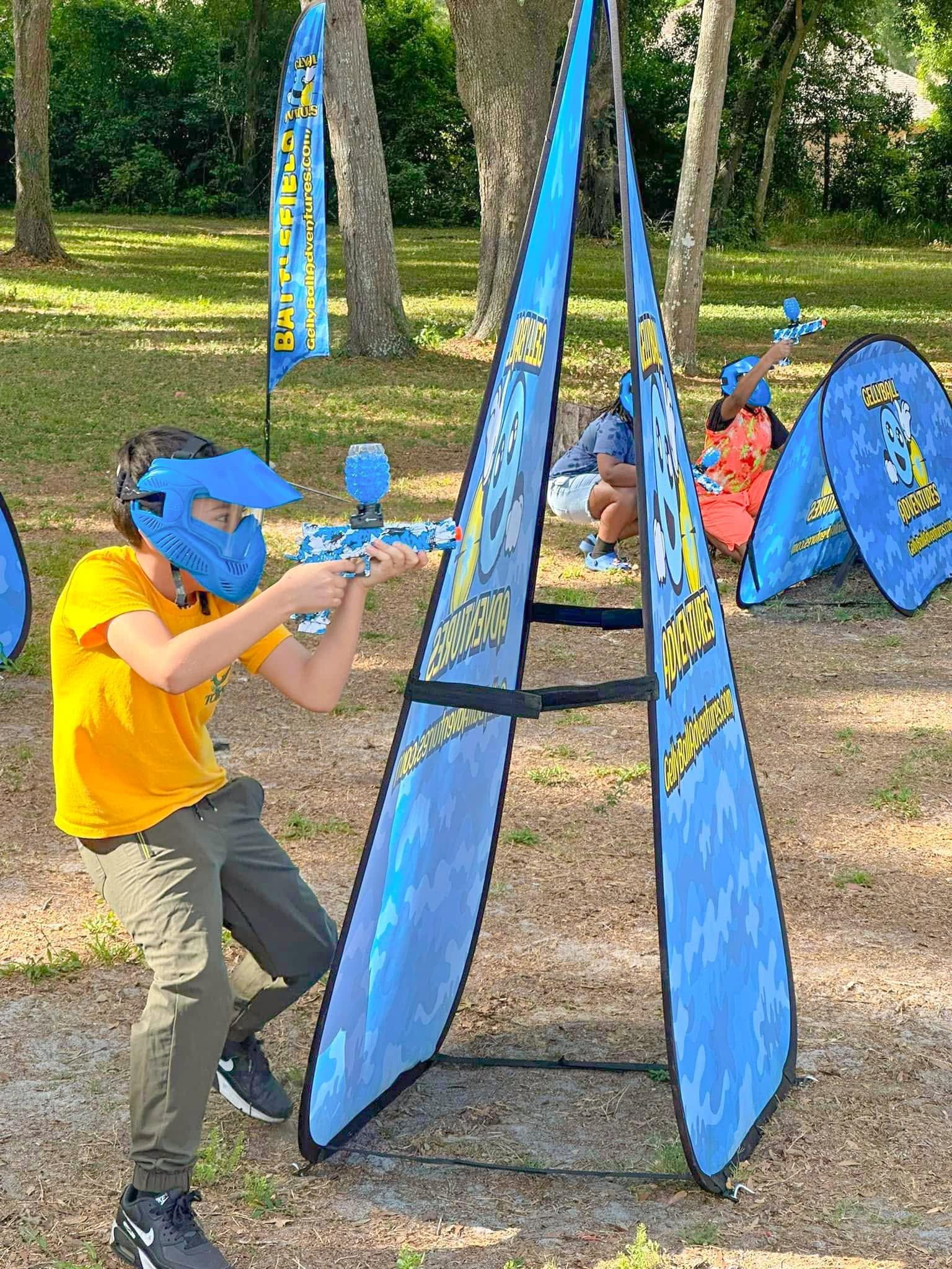A boy in a blue mask takes aim beside an A-frame bunker