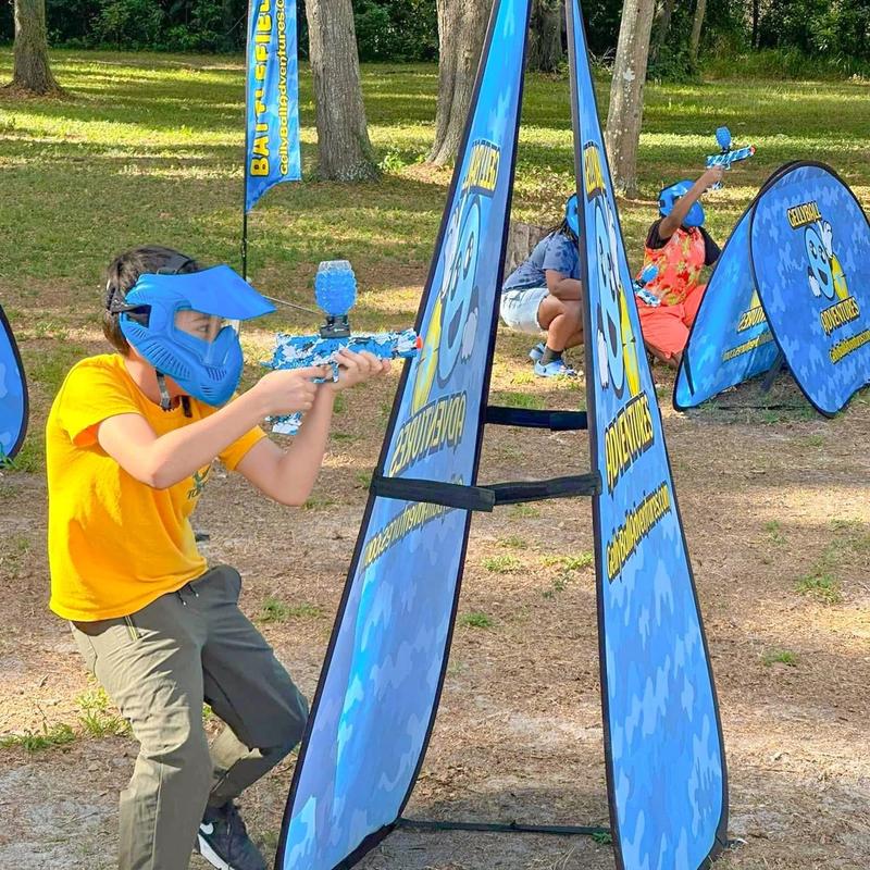 A boy in a blue mask takes aim beside an A-frame bunker
