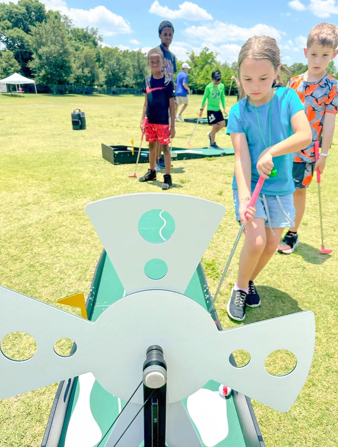 a girl putting through a windmill obstacle at an outdoor event
