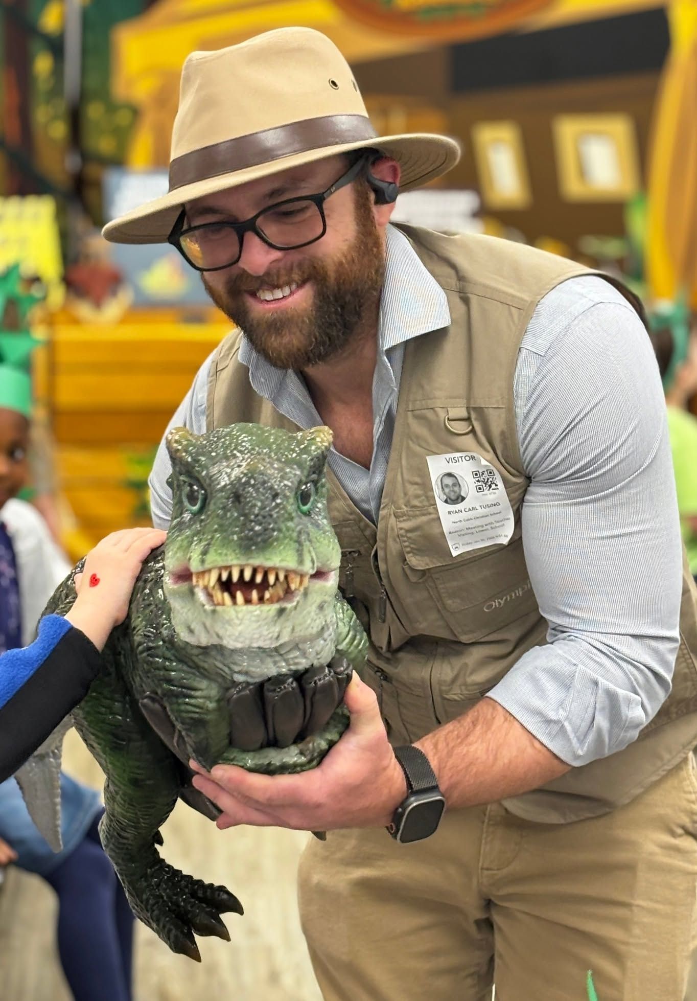 A child pats a dark green lifelike baby T. rex