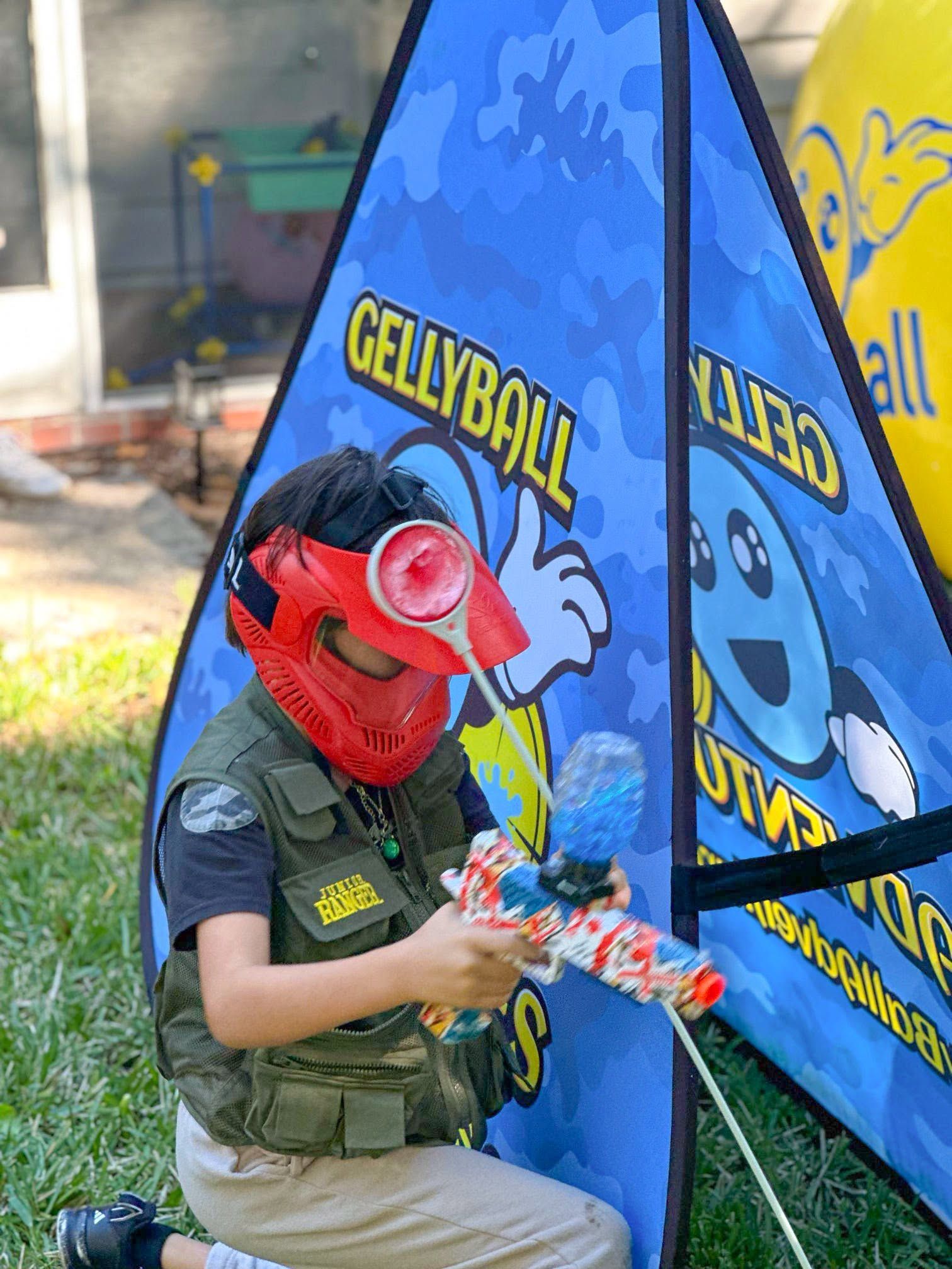 A boy in a red mask aims from behind a pop-up bunker