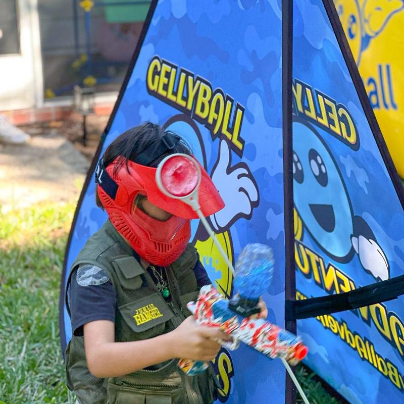 A boy in a red mask aims from behind a pop-up bunker