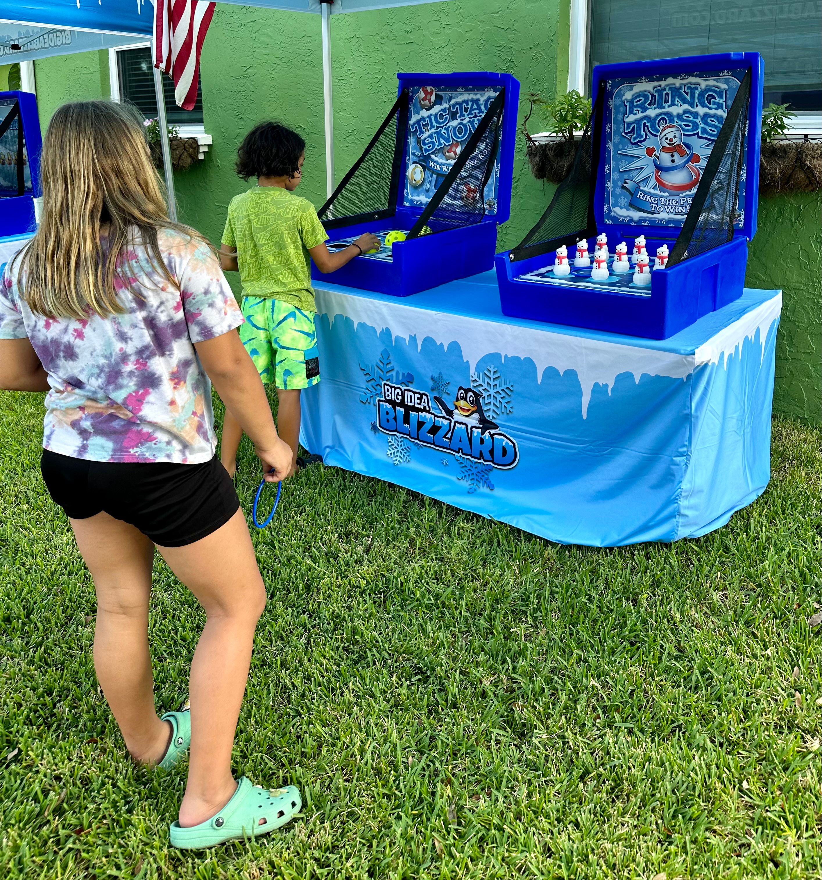 A girl holds a toss ring while a boy plays Tic Tac Snow under a Blizzard tent