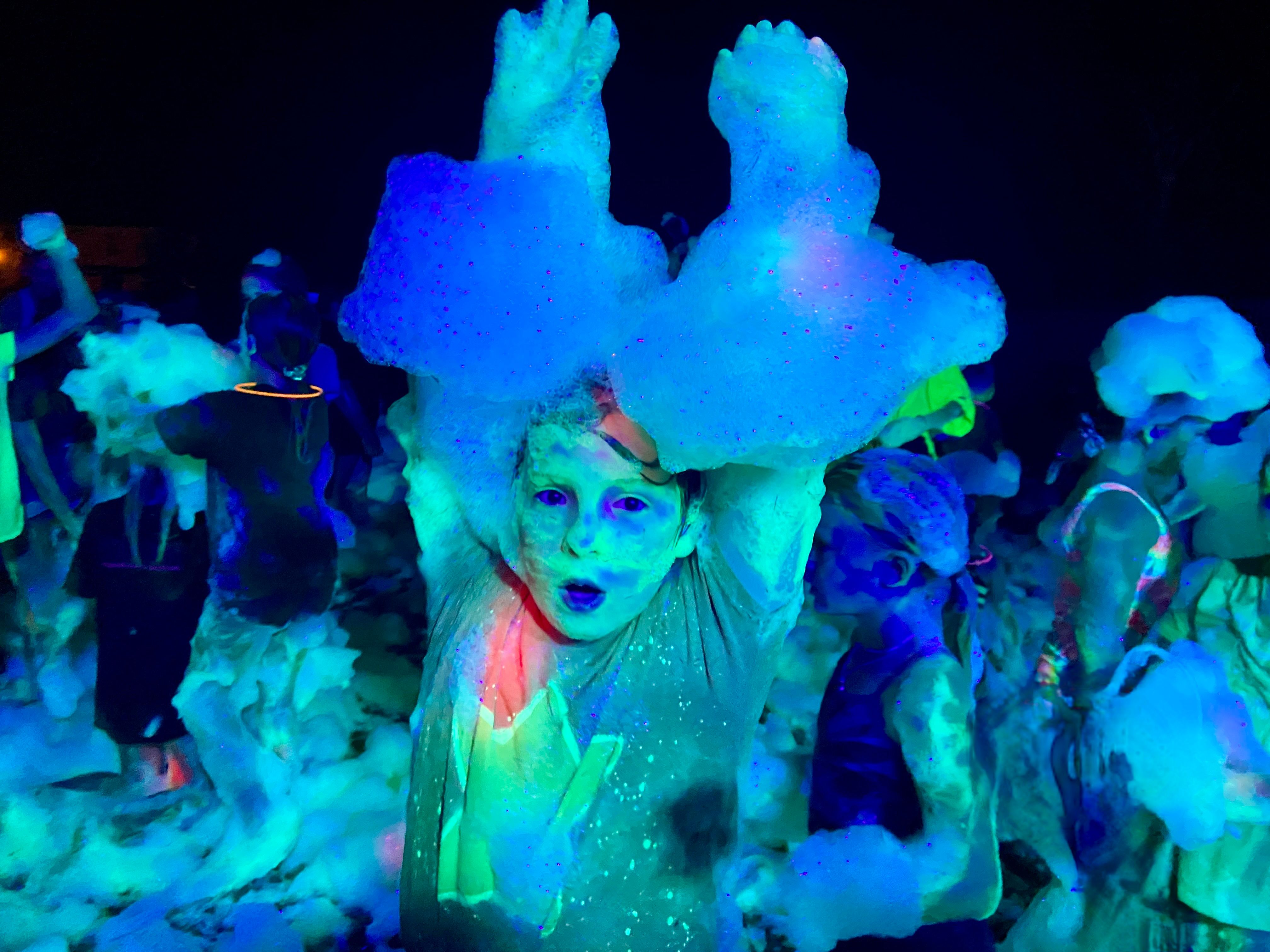Kids at a glow foam birthday party throwing foam into the air